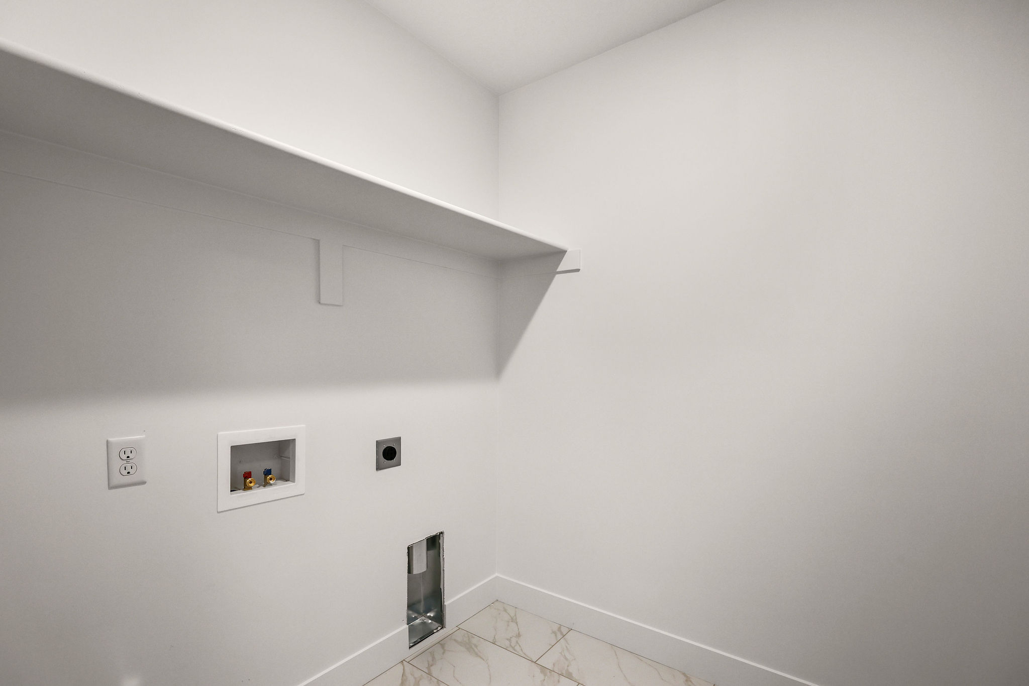 Utility area with an integrated shelving unit, electrical outlets, and appliance hookups