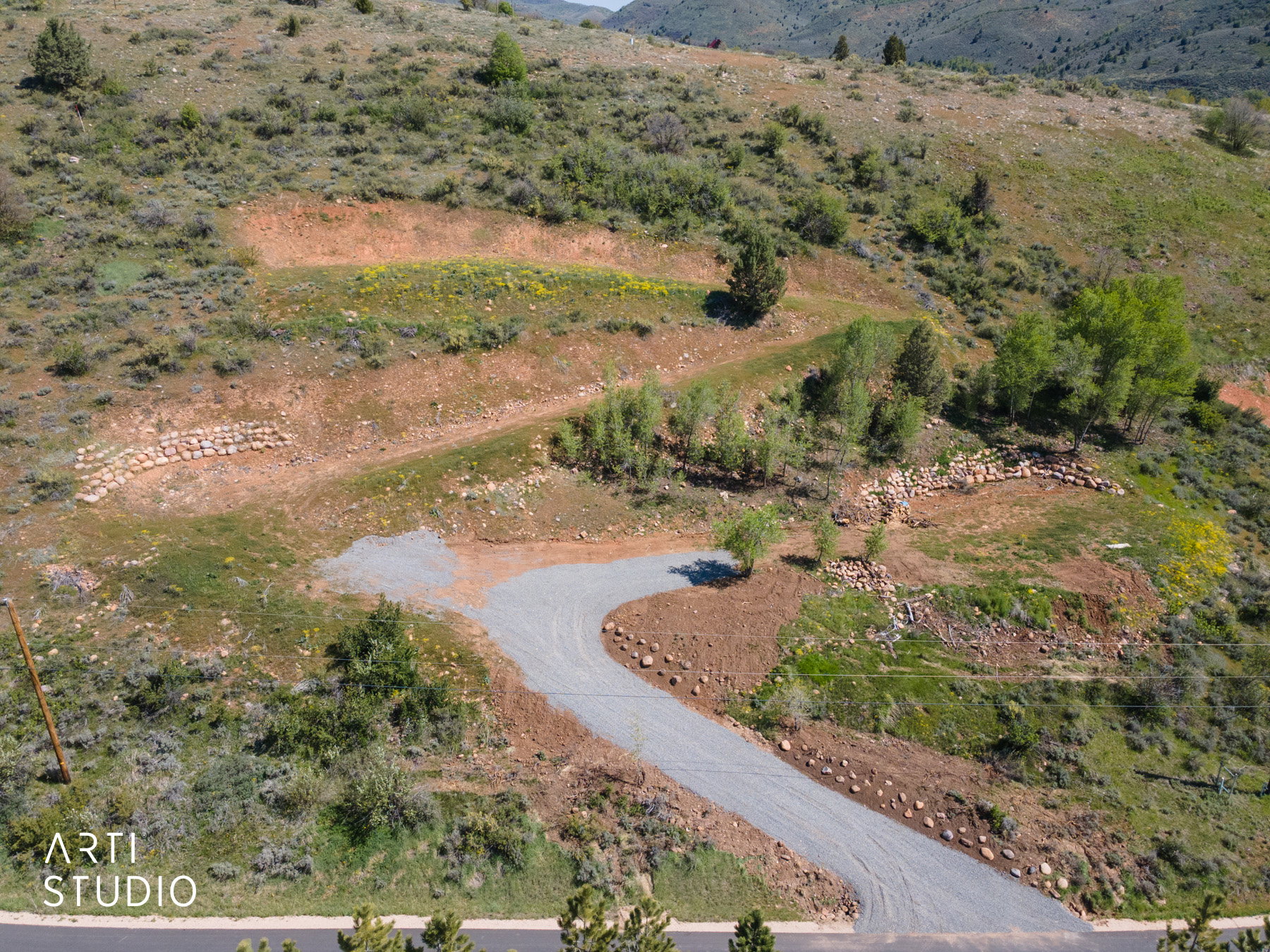 Gravel driveway winding through a sloped, undeveloped parcel