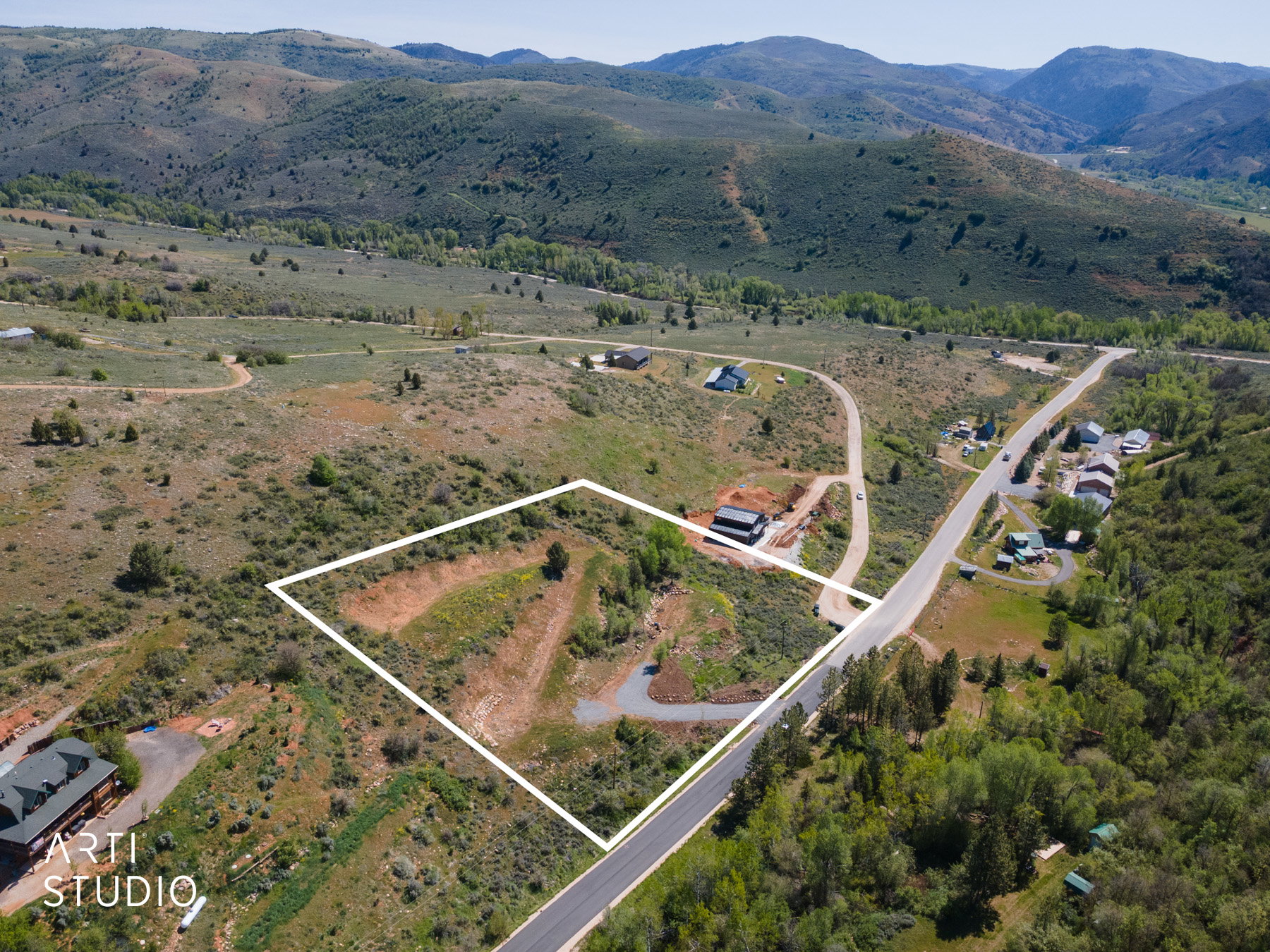Expansive lot featuring a sloped terrain, natural vegetation, and direct road frontage