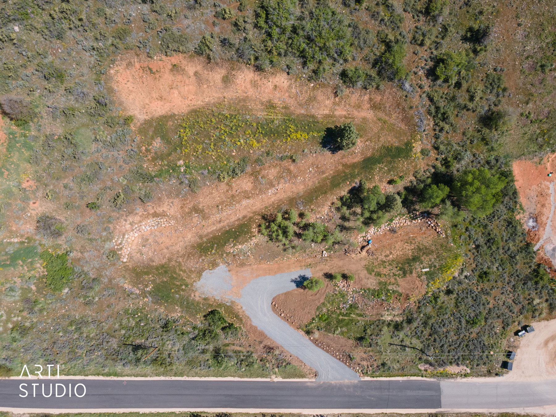 Expansive natural terrain with varied vegetation and established gravel driveway