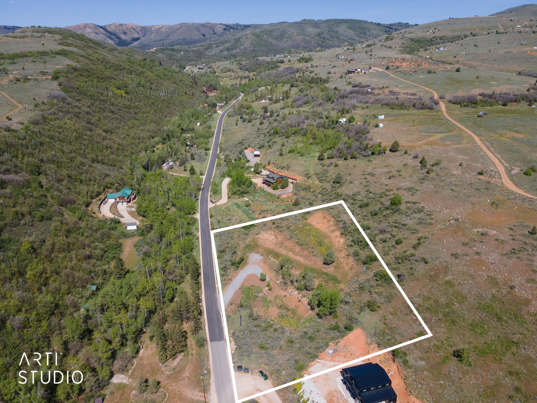 Expansive mountain acreage featuring a sloped topography, surrounding natural vegetation, and direct paved road frontage
