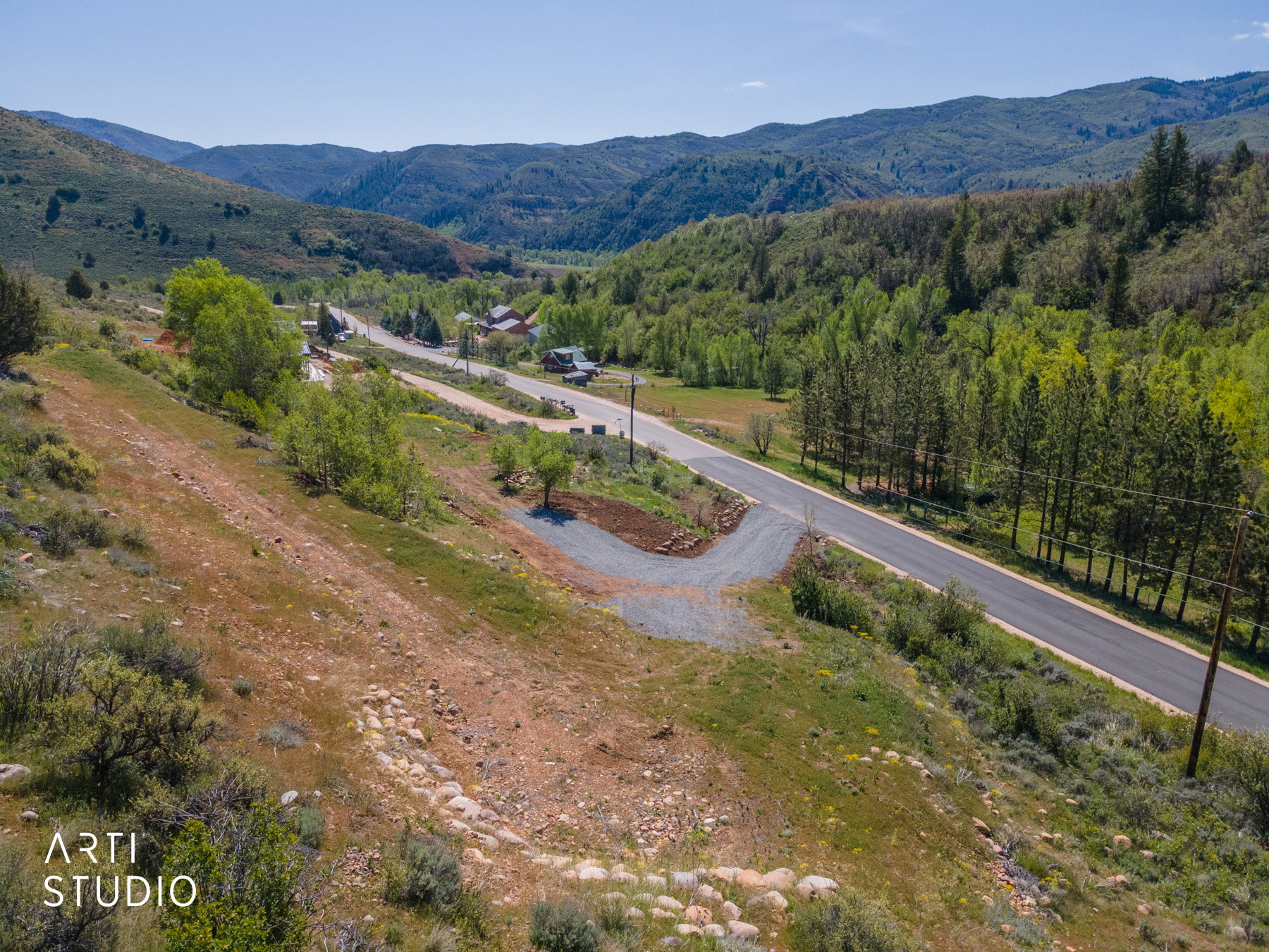 Expansive mountainous terrain featuring a paved road and a gravel turn-off