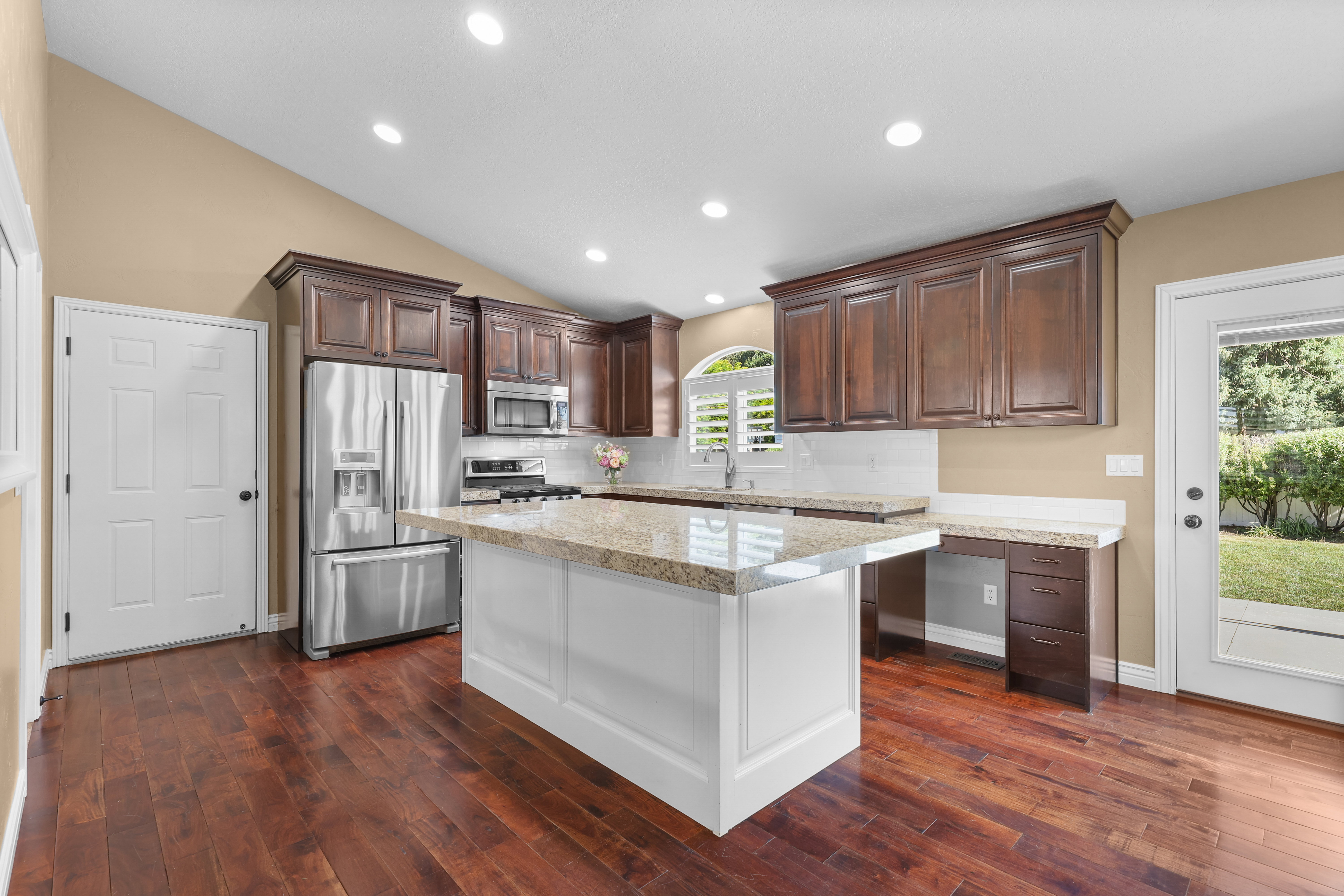 Kitchen featuring wood-finish flooring, dark wood cabinetry, and a white island with a light-toned countertop
