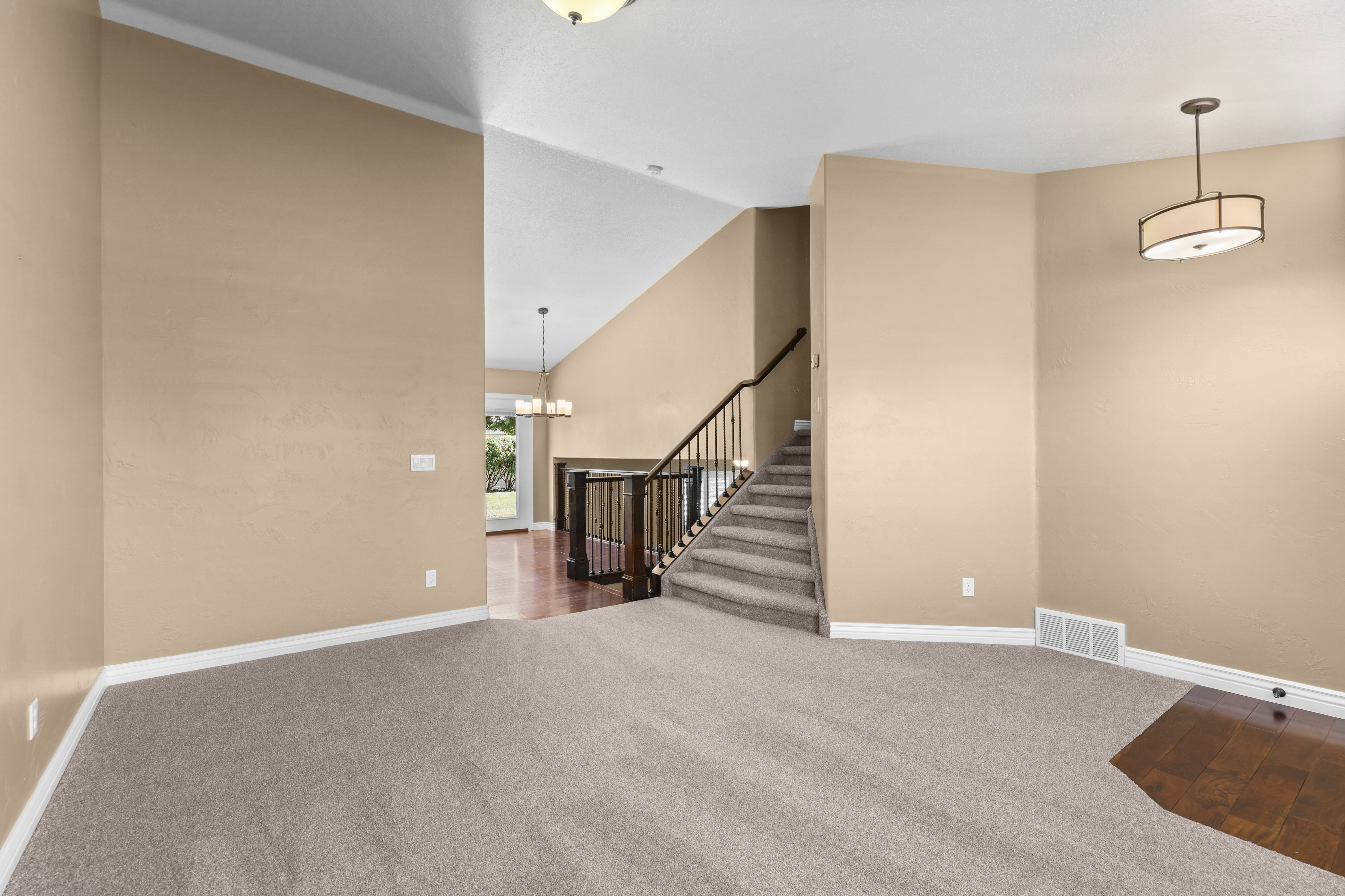 Spacious interior featuring vaulted ceilings and a blend of carpet and wood-finish flooring