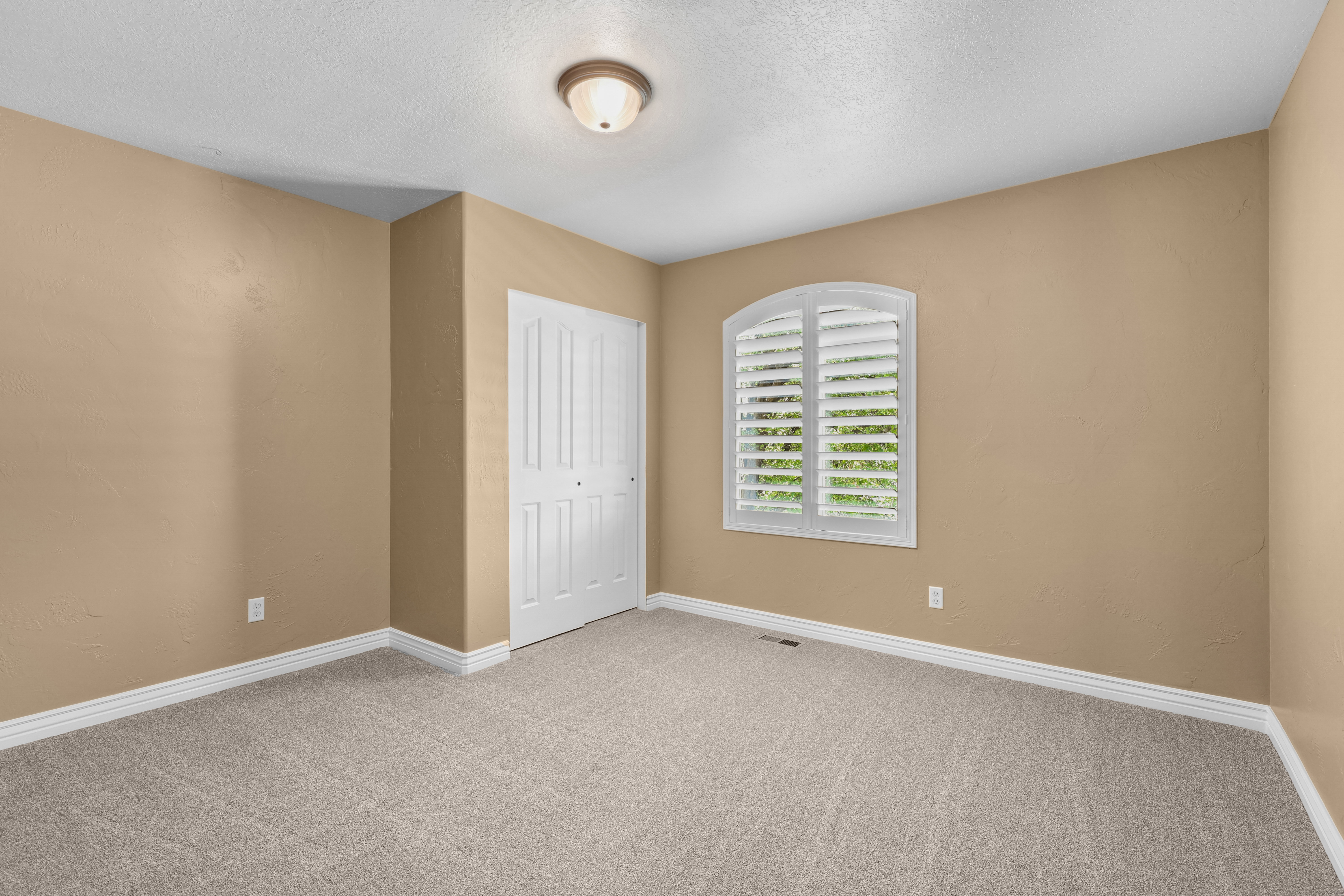 Carpeted interior space featuring neutral tone walls, white baseboards, and a white bi-fold closet door