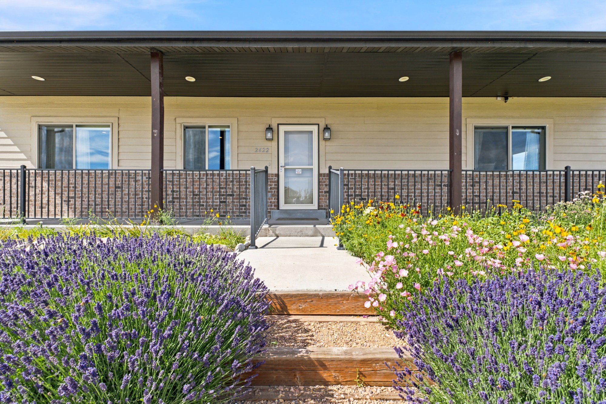 Covered front porch featuring a metal railing system, brick siding, and light-toned horizontal siding