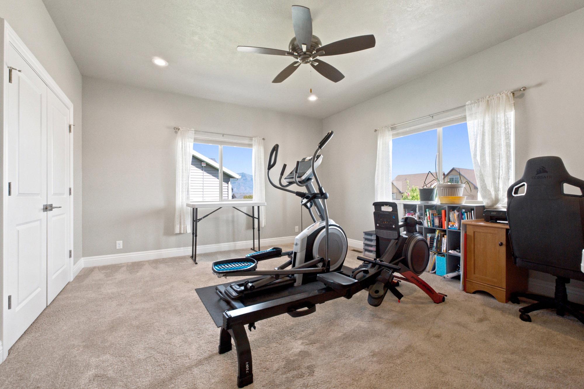 Spacious room featuring carpeting, two windows, and a ceiling fan