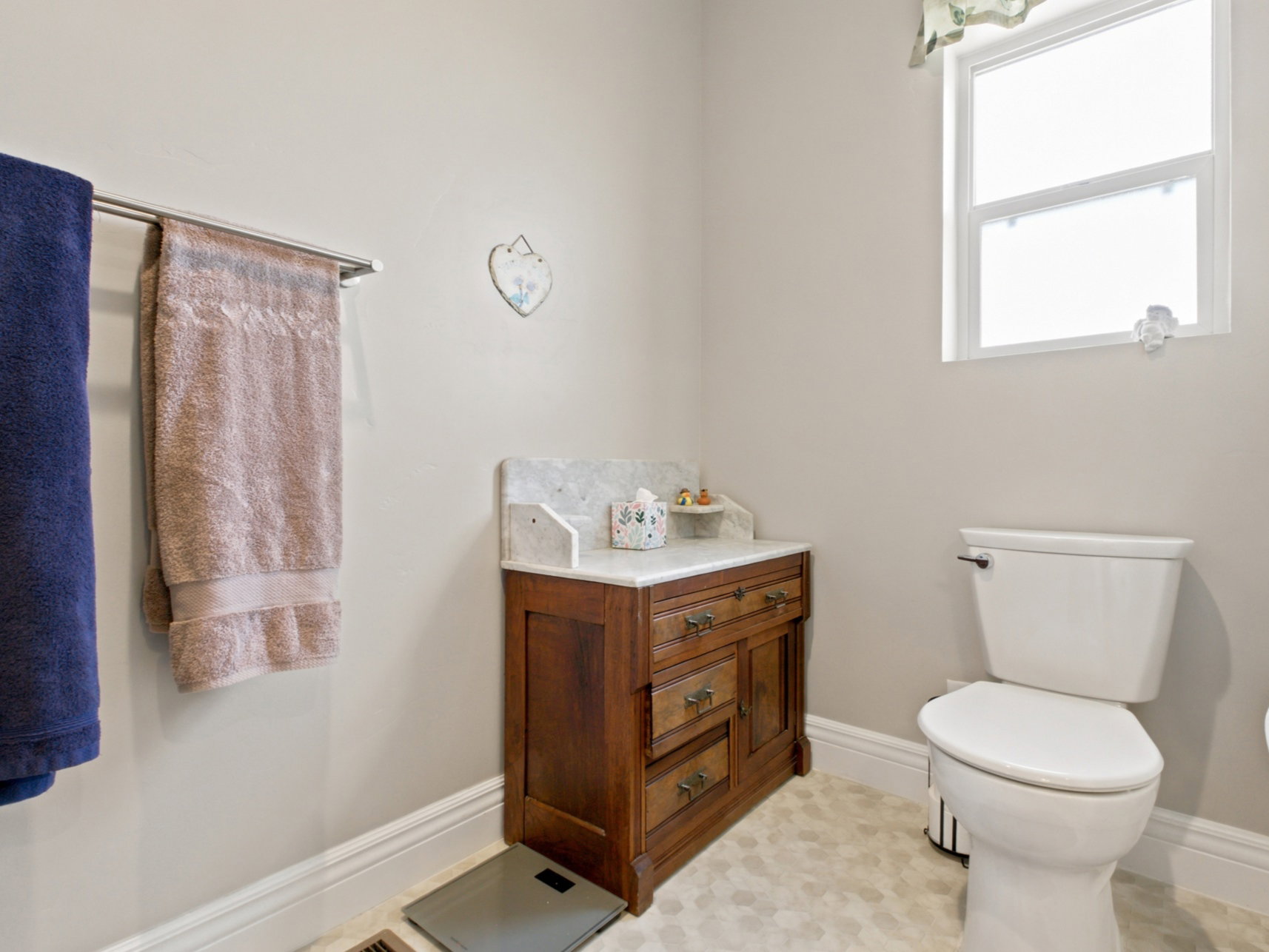 Bathroom featuring a white toilet, window with white trim, and light hexagonal tile flooring