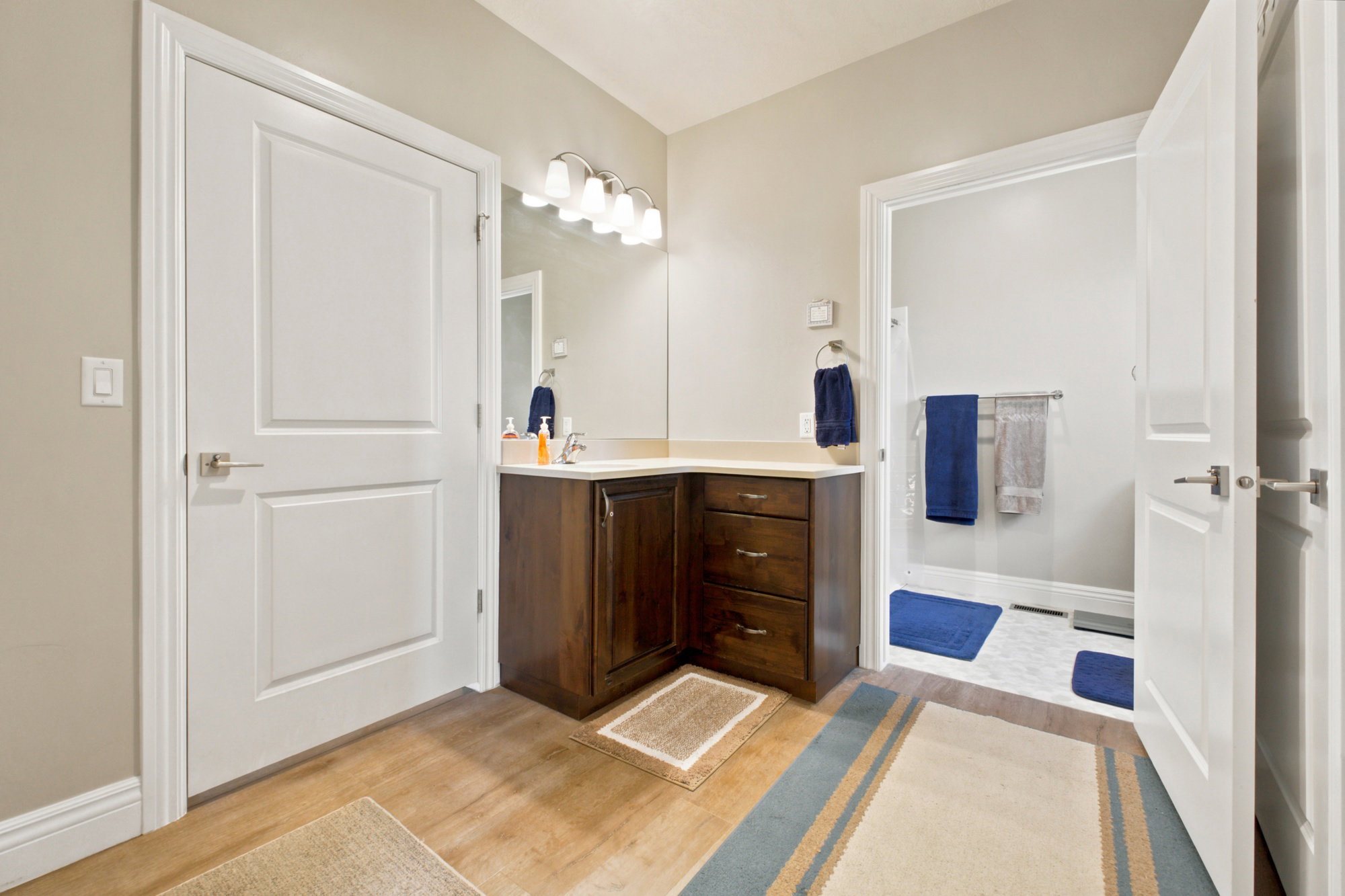 Bathroom featuring a corner wood-finish vanity with a light-colored countertop and a mirror above