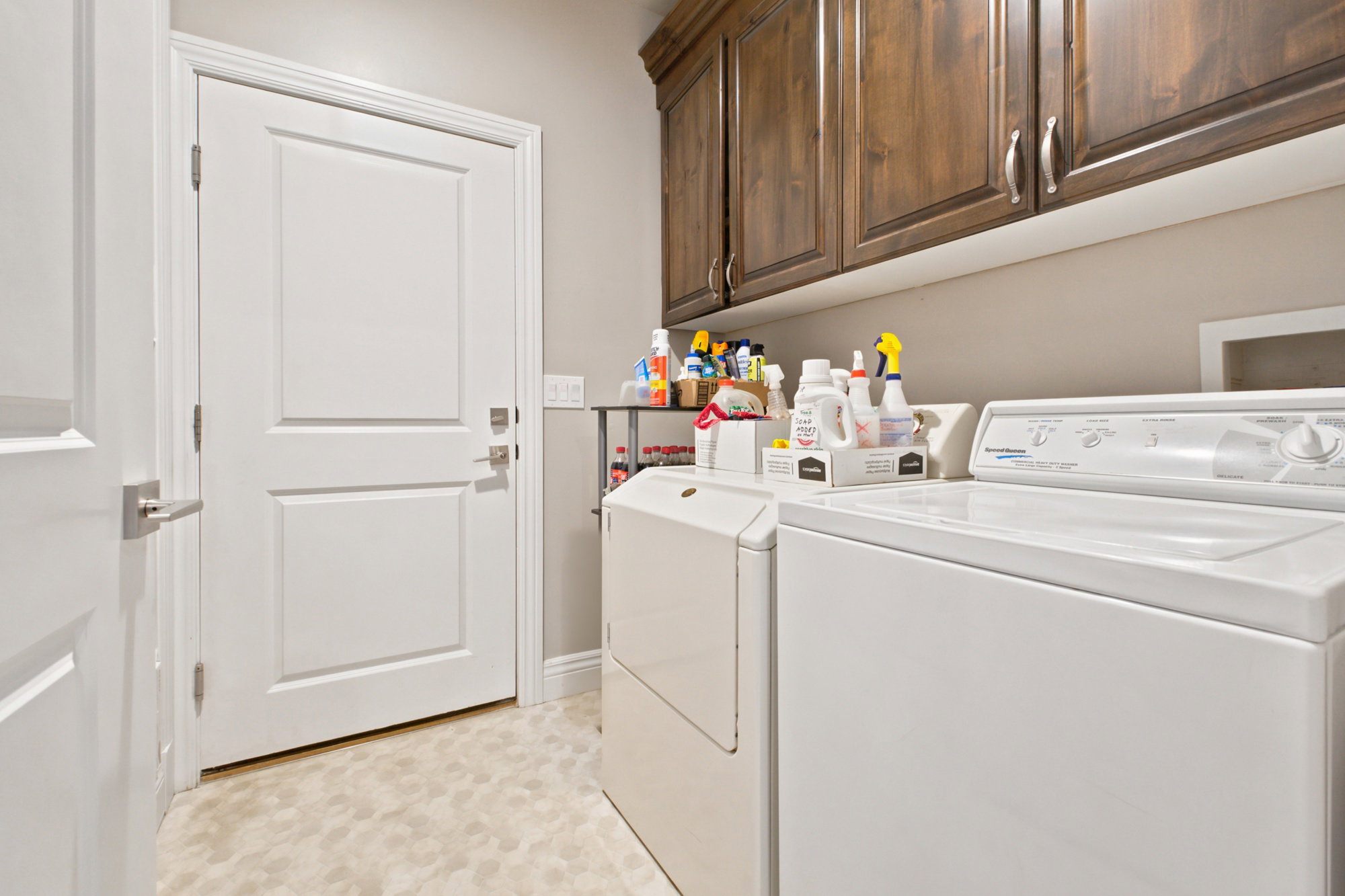 Laundry area with wood-finish cabinetry, white paneled door, and light-toned flooring
