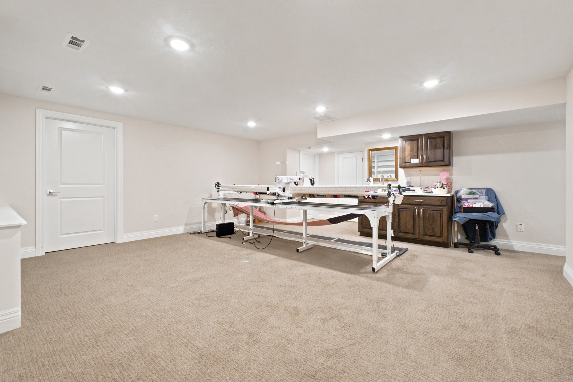 Family room with recessed lighting, light-toned carpeting, and a kitchenette with dark wood-finish doors and drawers