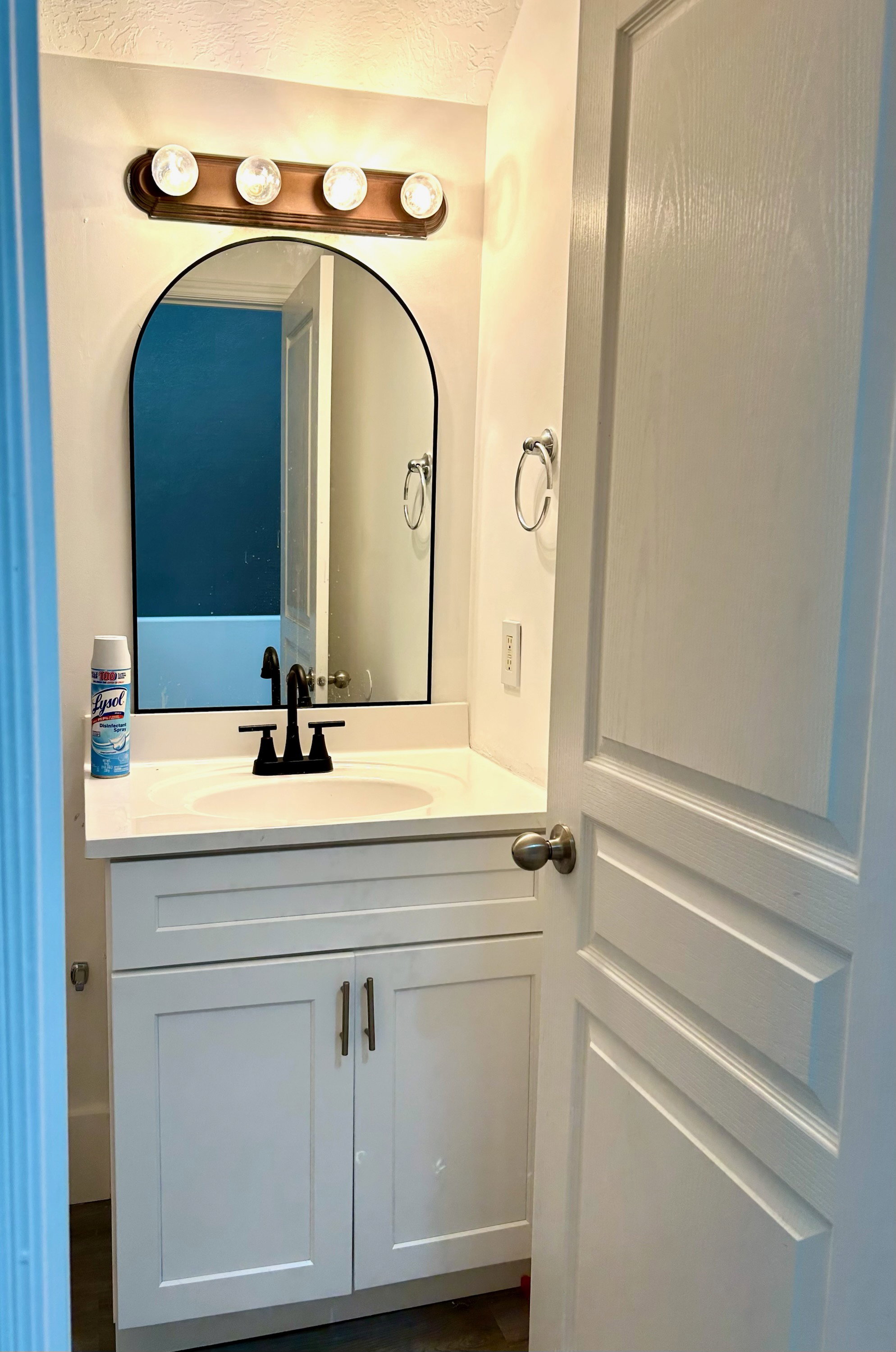 Bathroom vanity featuring a white shaker-style cabinet, a white countertop, and a matte black faucet