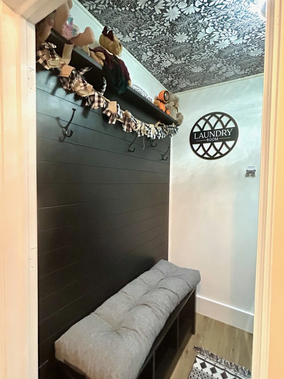 Hallway entryway featuring black shiplap, integrated shelving, and a built-in bench