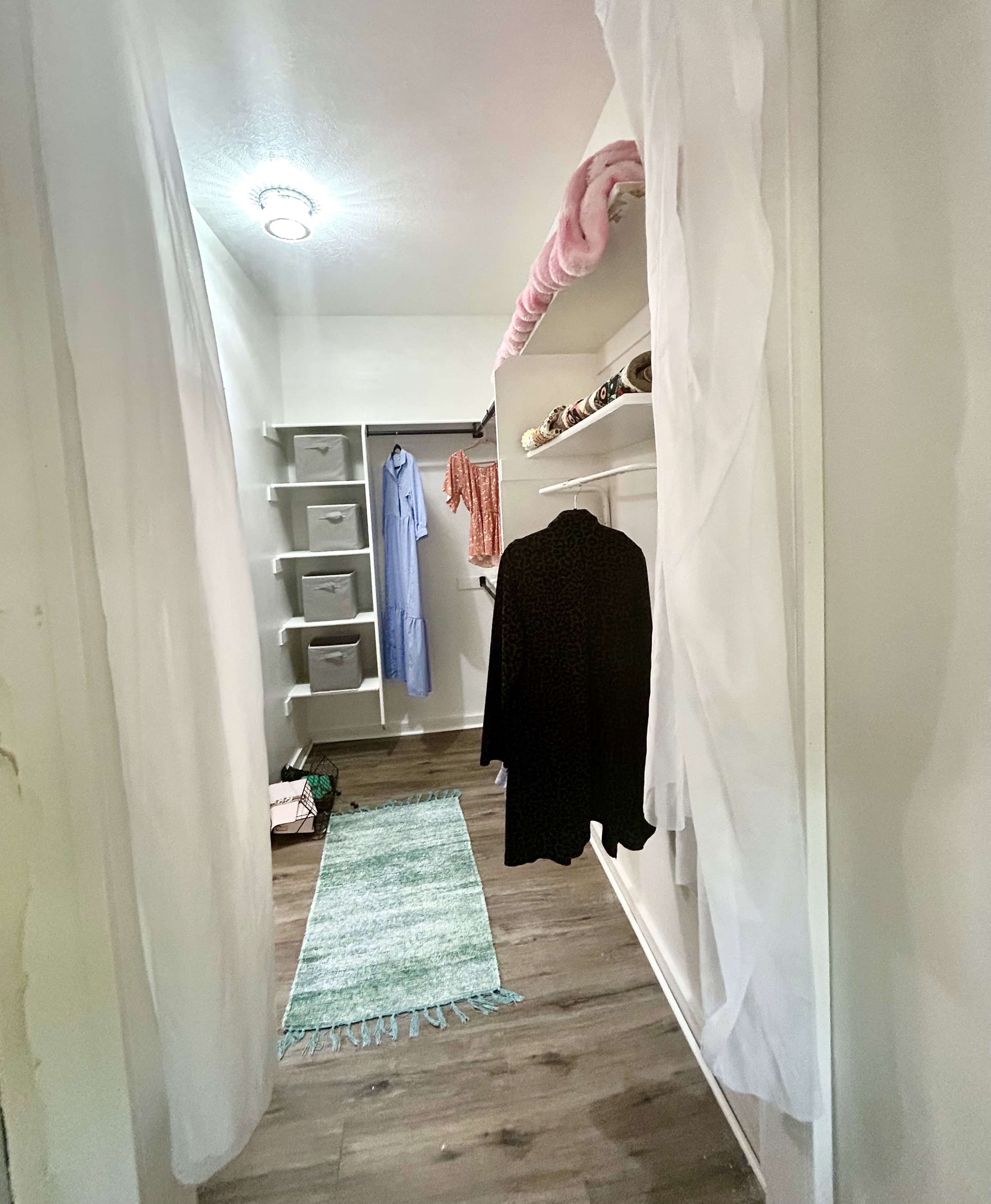 Custom closet with built-in shelving, hanging rods, and wood-finish flooring