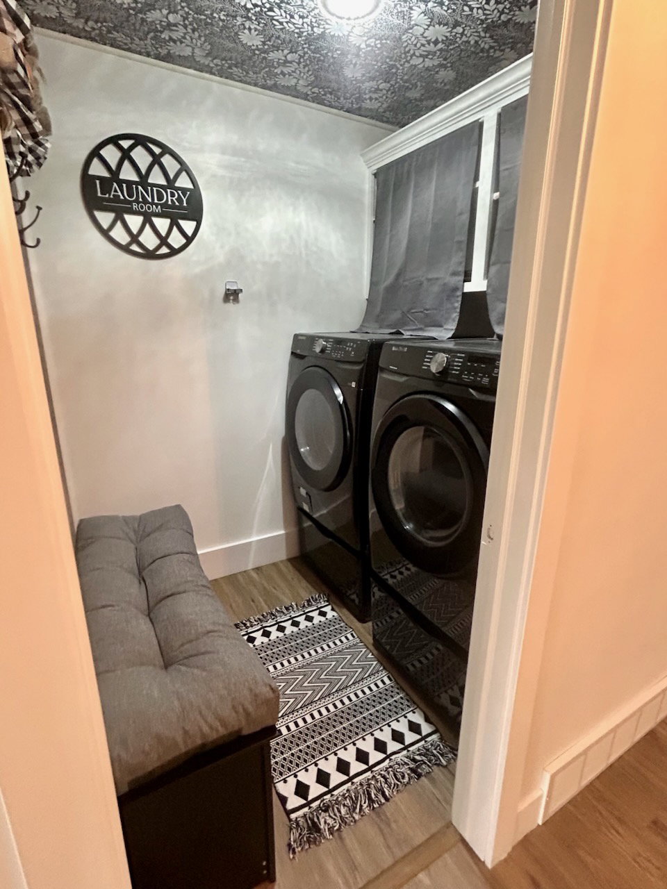 Dedicated laundry area featuring wood-finish flooring, a patterned ceiling treatment, and a wall-mounted light fixture
