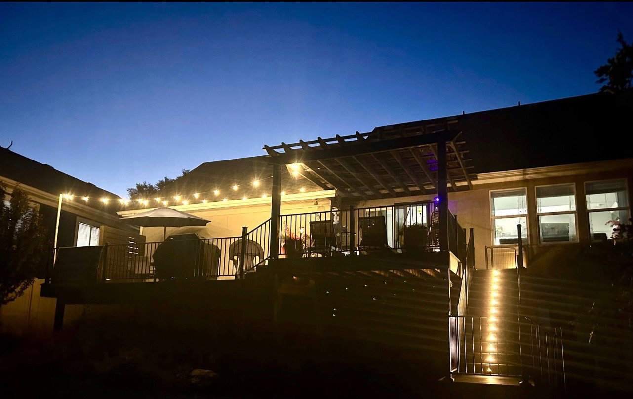 Multi-level deck with a pergola-covered patio, string lighting, and integrated stair lighting