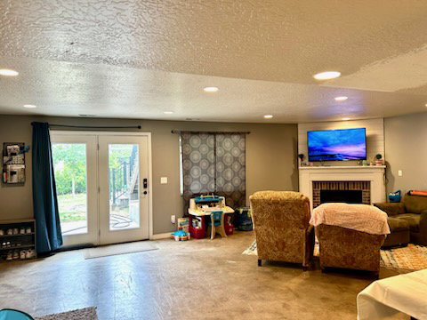 Recessed lighting illuminates the living area, featuring a fireplace with a white mantel and a brick surround