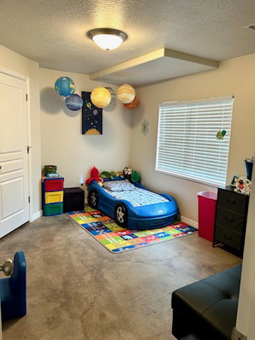 Spacious room featuring durable concrete flooring, a large window with horizontal blinds, a flush mount ceiling light, and a white paneled door