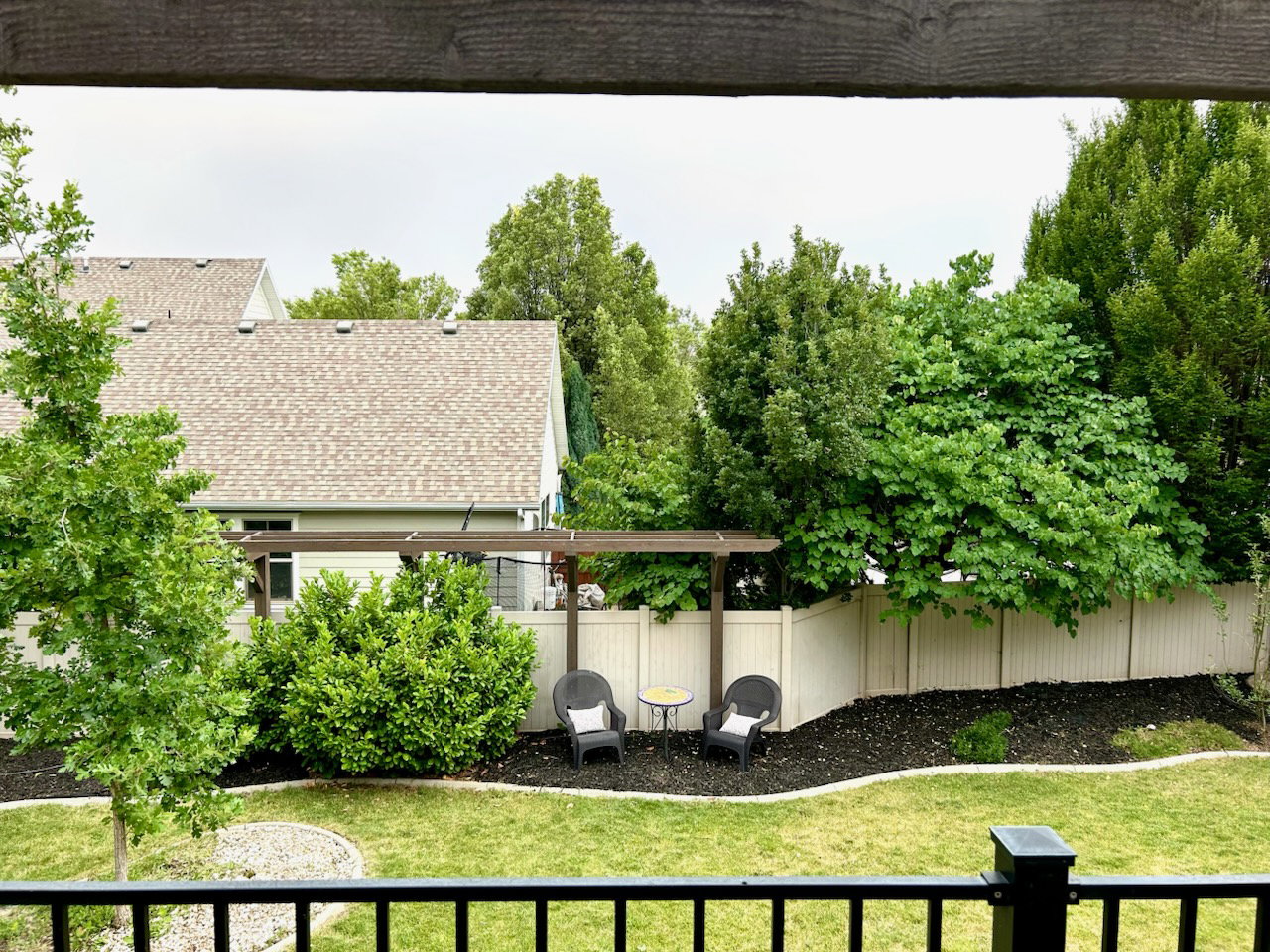 Expansive backyard featuring a lush lawn, mature trees, and a privacy fence