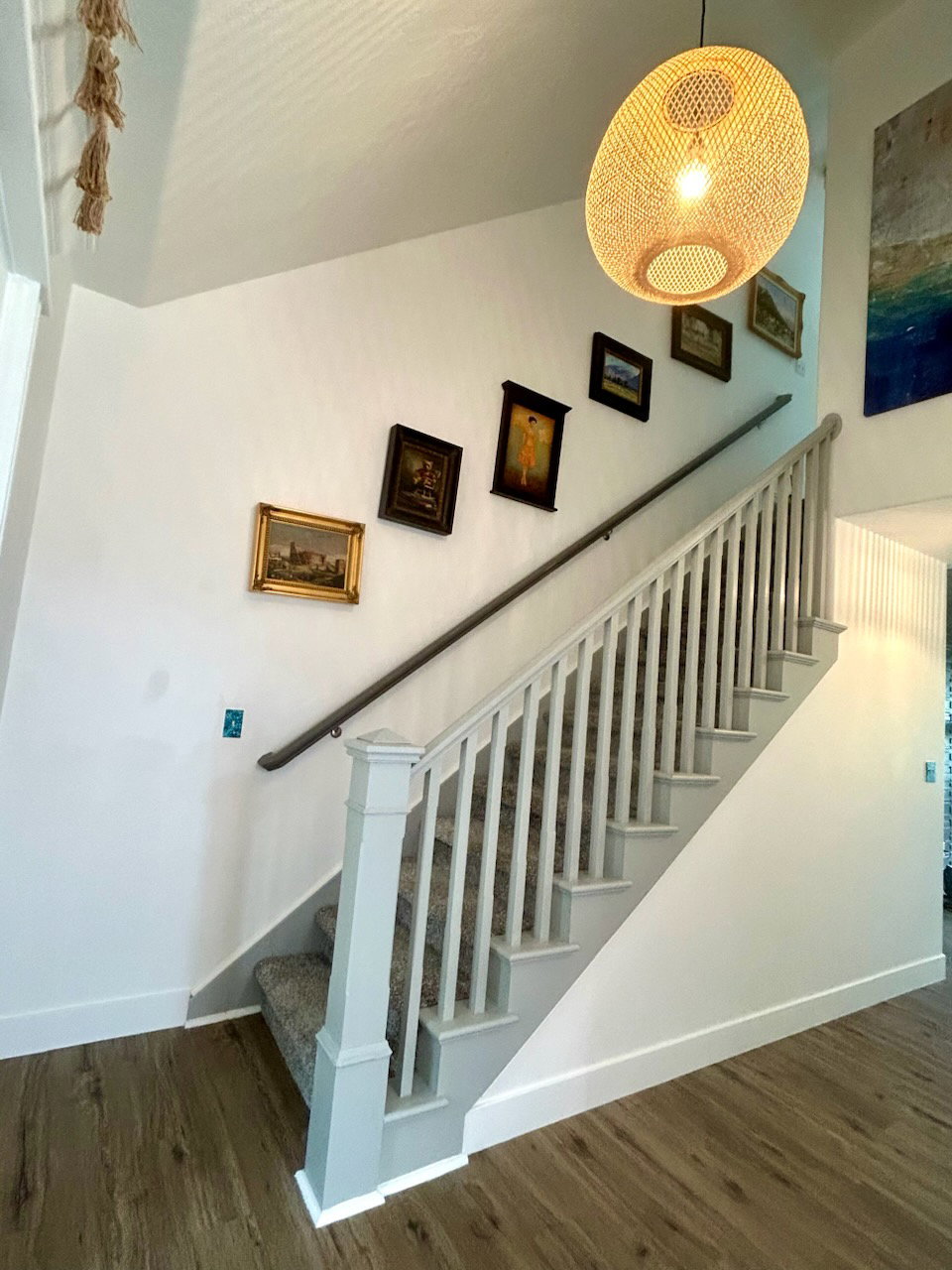 Staircase featuring light-toned wood-finish flooring, white risers, and a carpeted tread