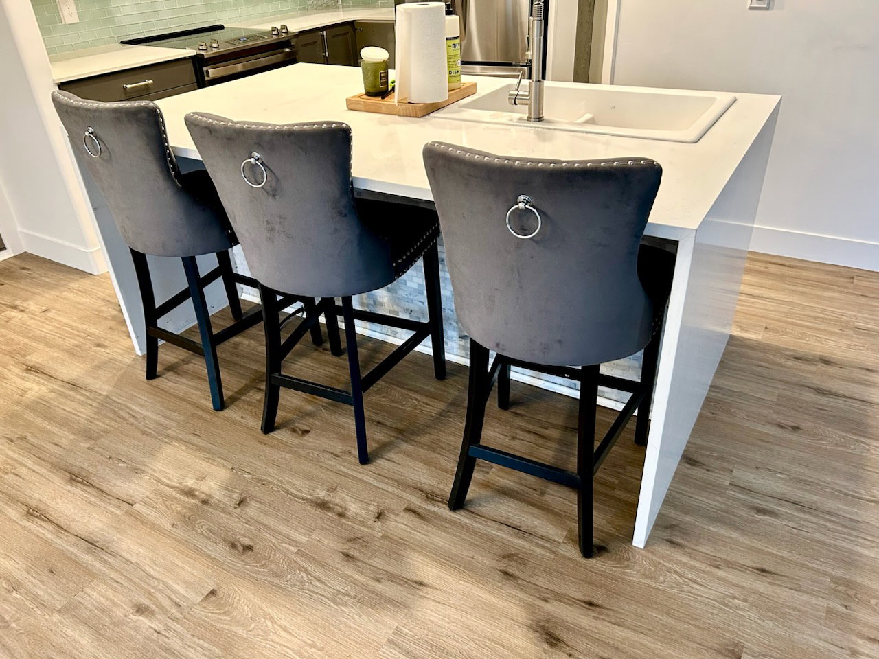 Kitchen island with an integrated sink, a contemporary faucet, and a light-toned countertop