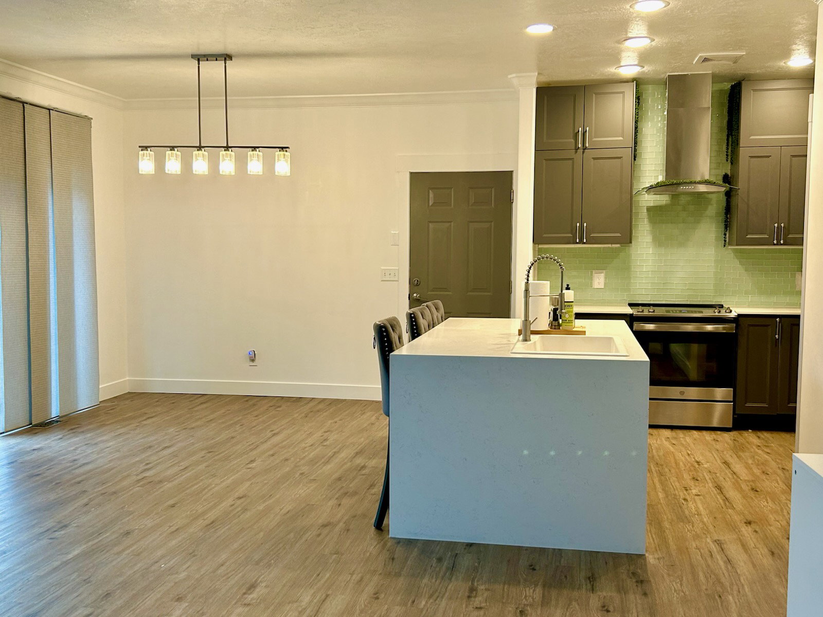 Modern kitchen featuring a waterfall island with an undermount sink, stainless steel appliances, a subway tile backsplash, and recessed lighting