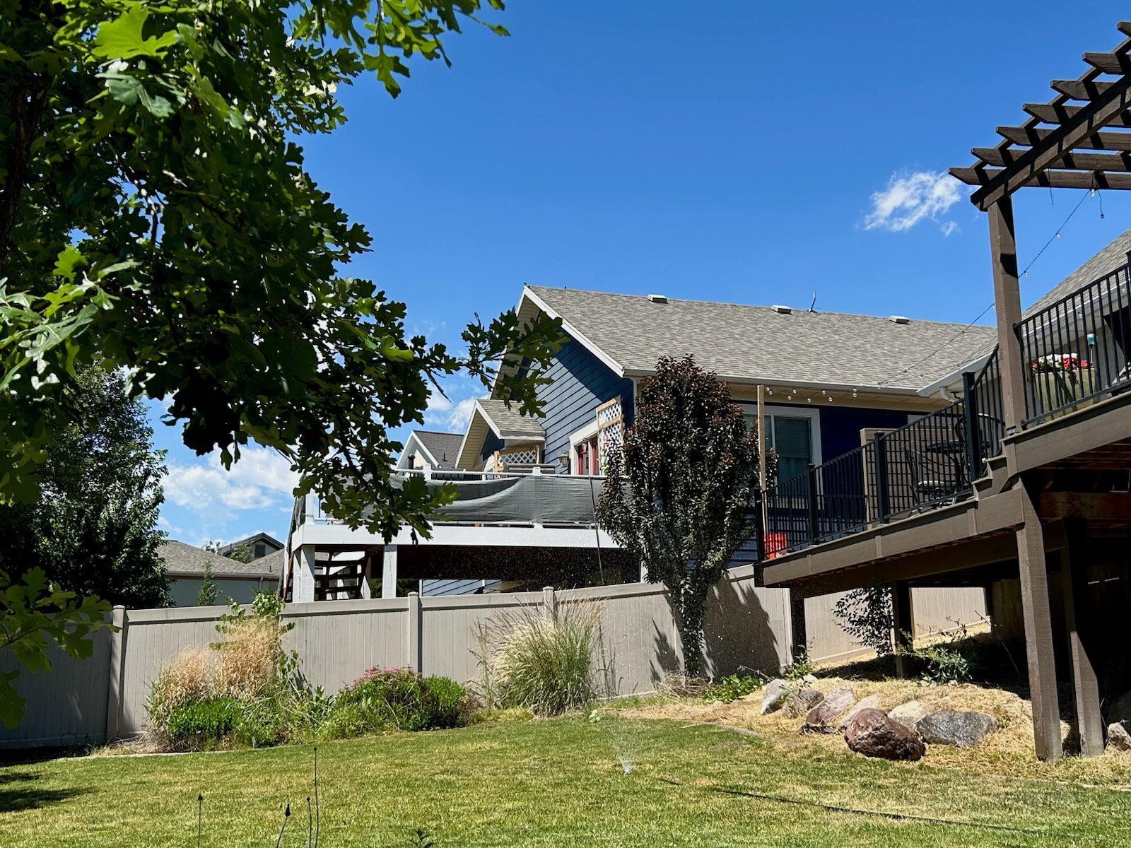 Spacious backyard featuring a manicured lawn, established landscaping, and a sturdy privacy fence