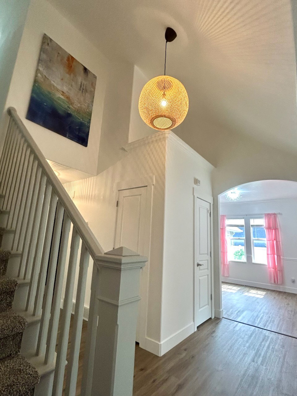 Entryway featuring a woven pendant light fixture, vaulted ceiling, and wood-finish flooring