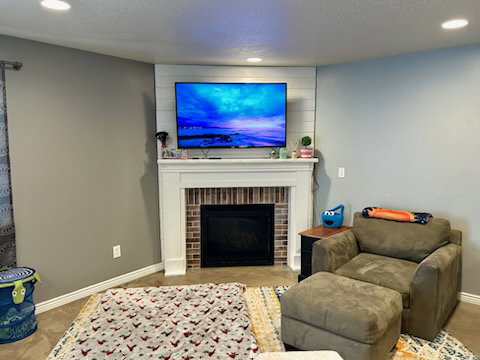 Fireplace featuring a white mantel, brick surround, and shiplap accent wall