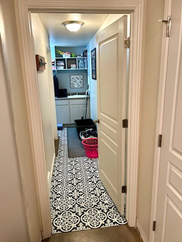 Laundry area featuring patterned flooring, built-in cabinetry, an integrated sink, and overhead shelving
