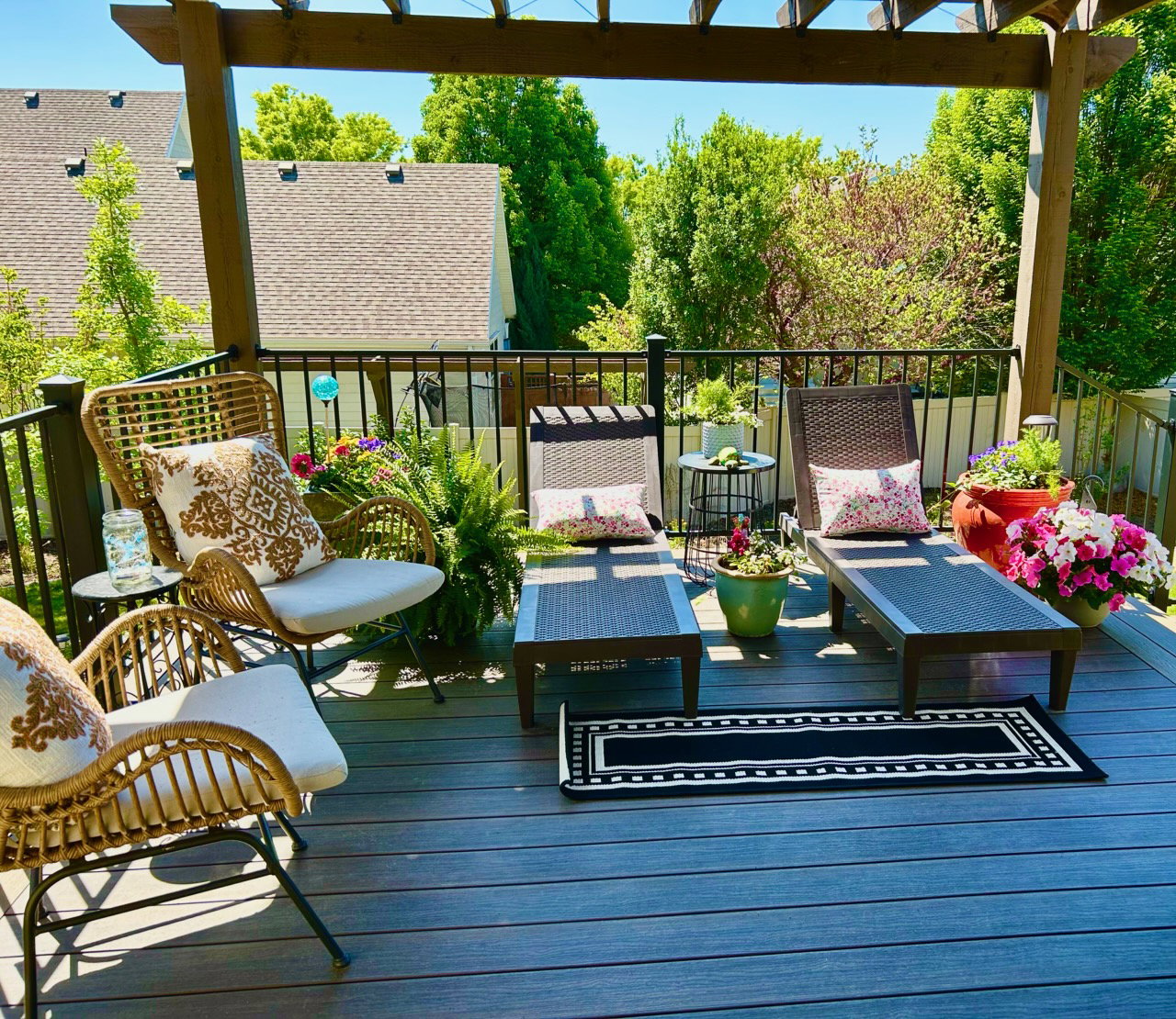 Spacious outdoor deck featuring composite decking, a wooden pergola, black metal railings, and ample room for seating