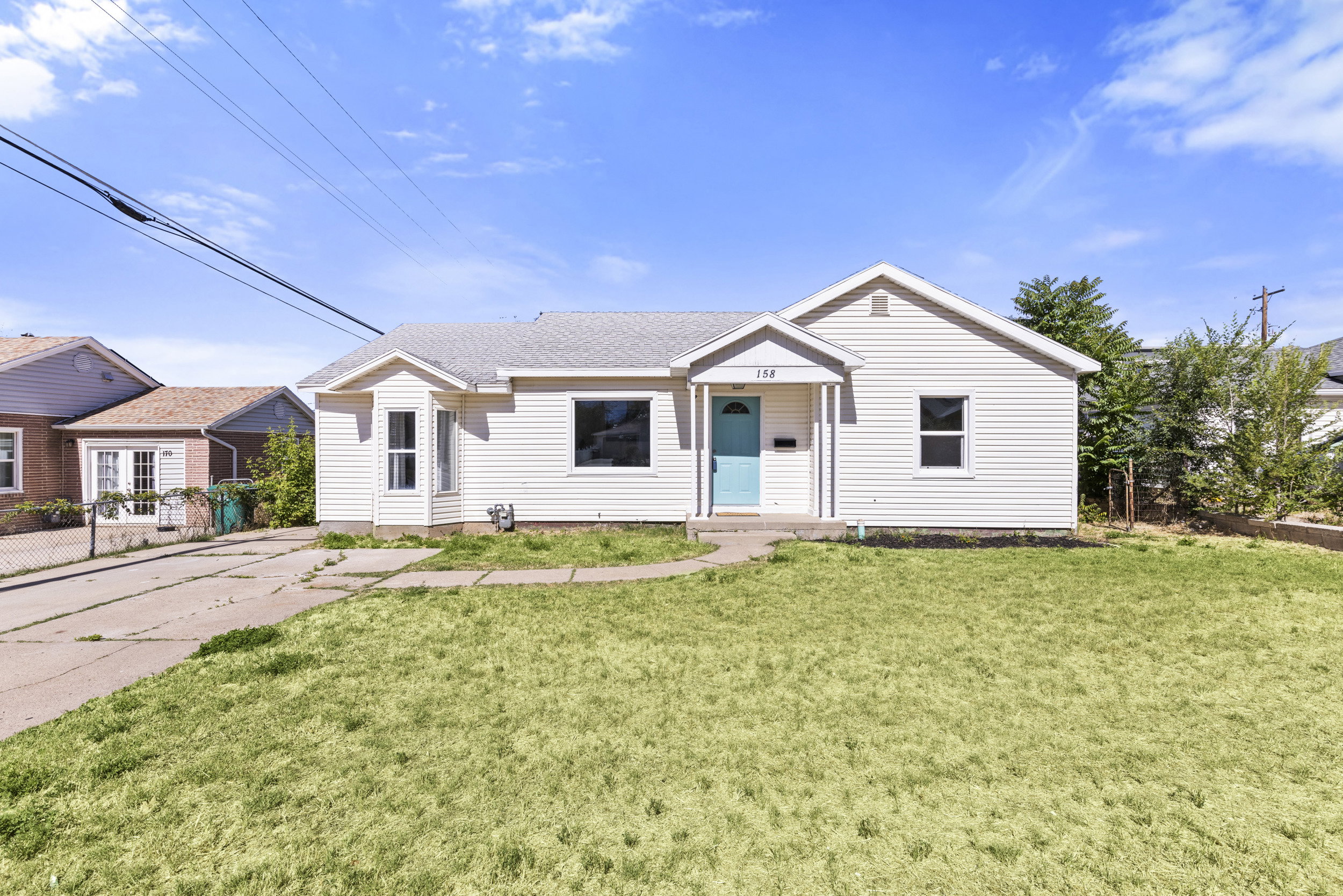 Single-story residence featuring white siding, a contrasting teal front door, and a bay window