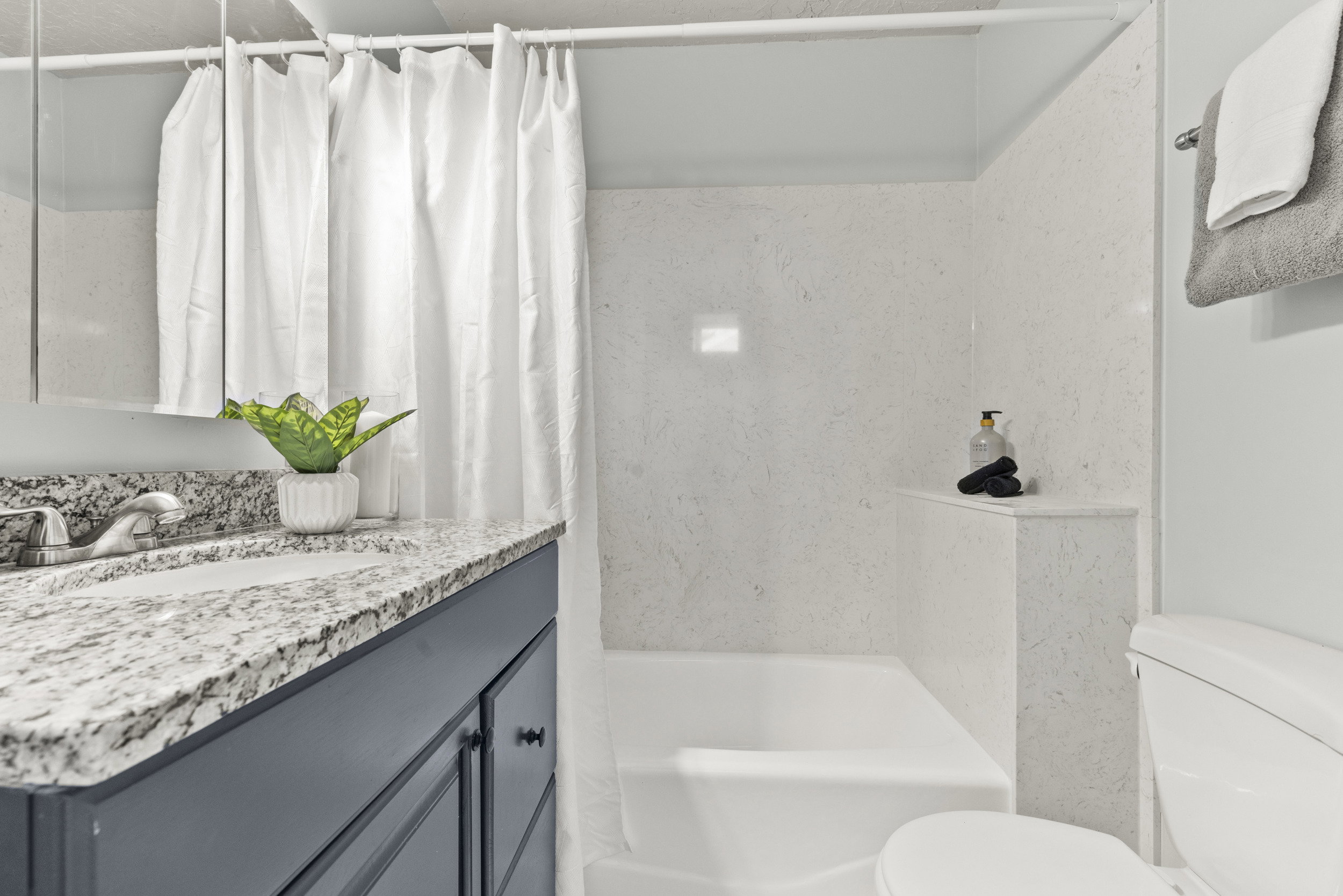 Bathroom featuring a built-in tub and shower combination with white paneling