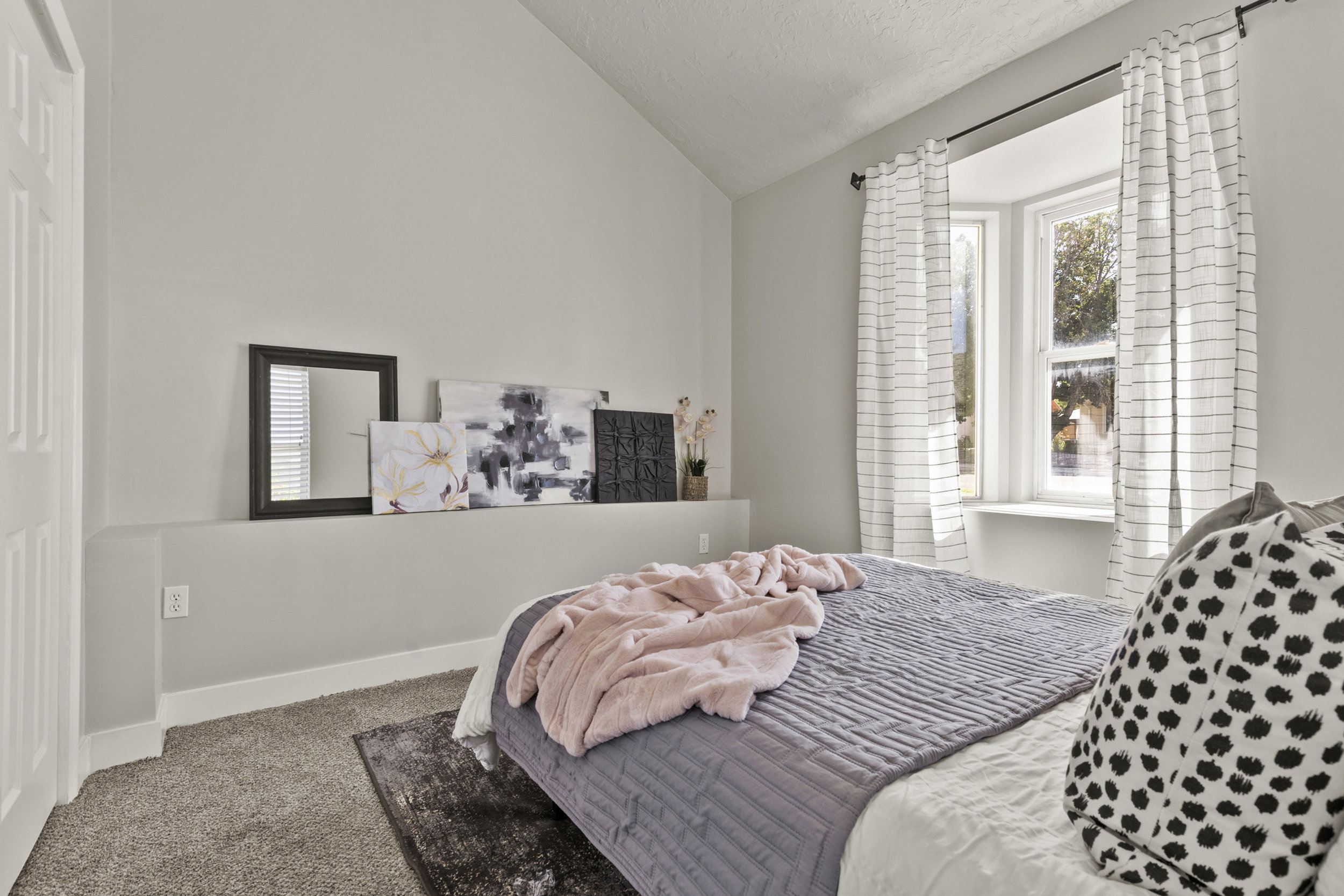Bedroom featuring a built-in window seat, vaulted ceiling, and neutral-toned wall paint