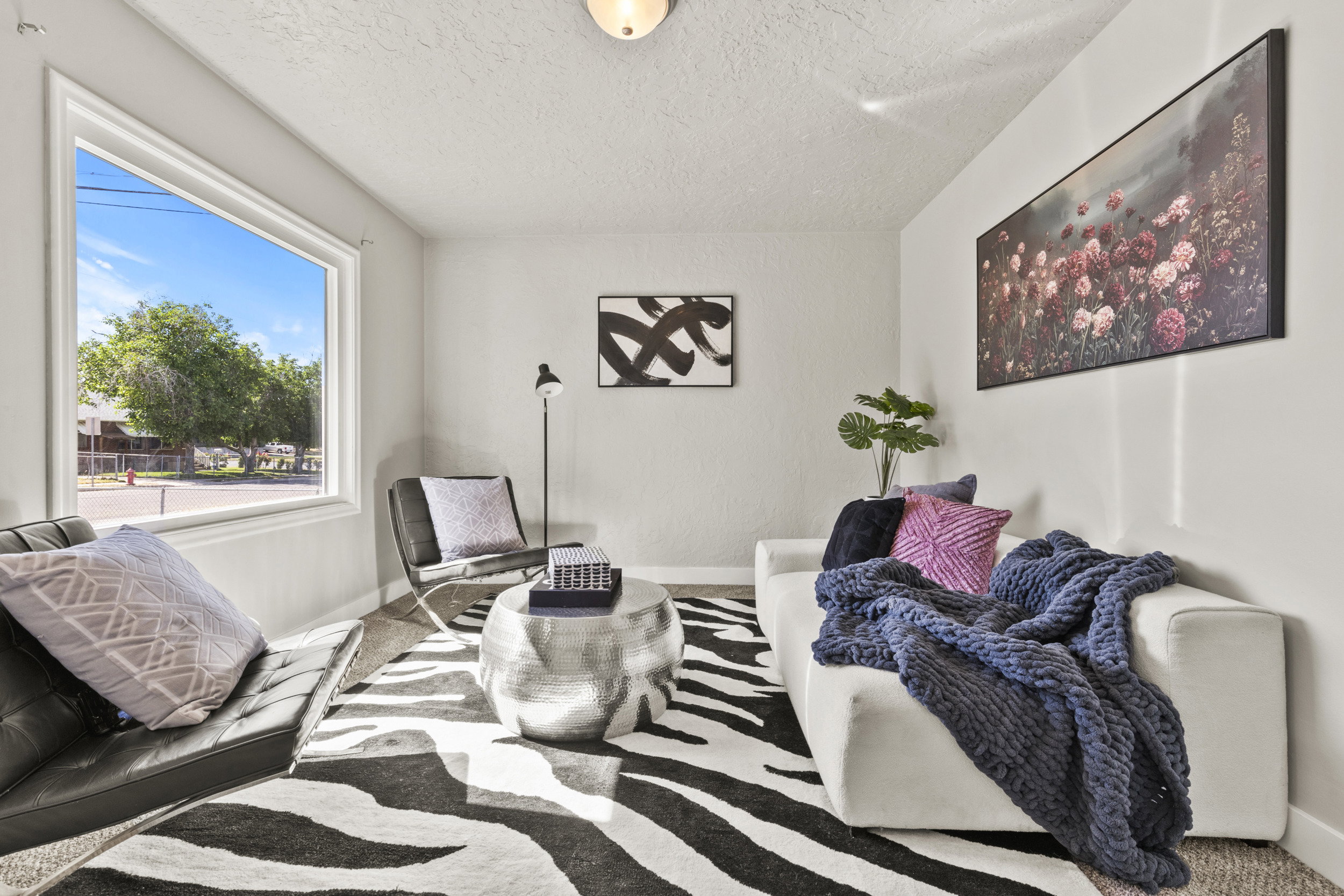 Living area with a large picture window, textured ceiling, light-toned wall paint, and carpeted flooring
