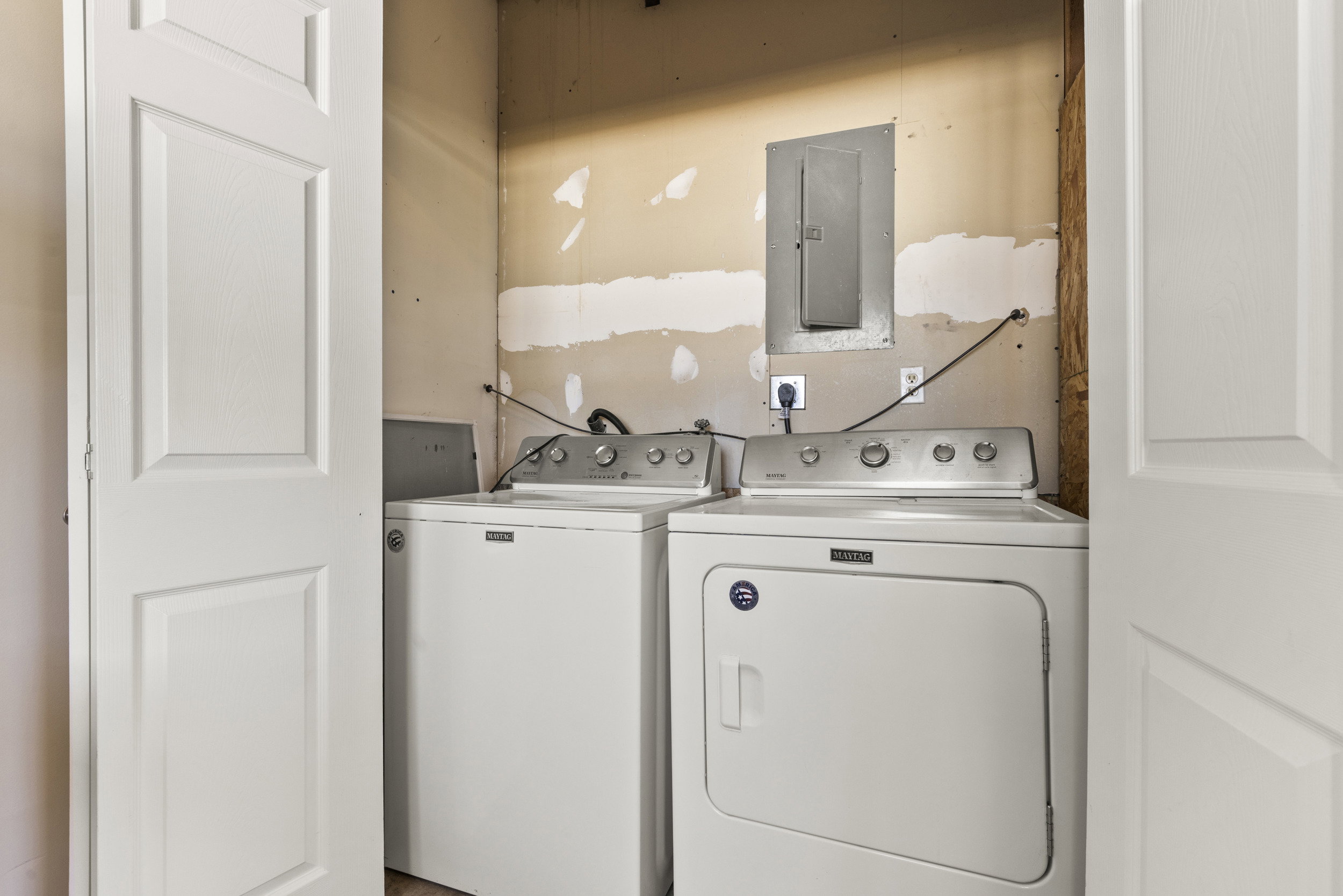 Laundry area with white paneled bifold doors and a visible electrical panel