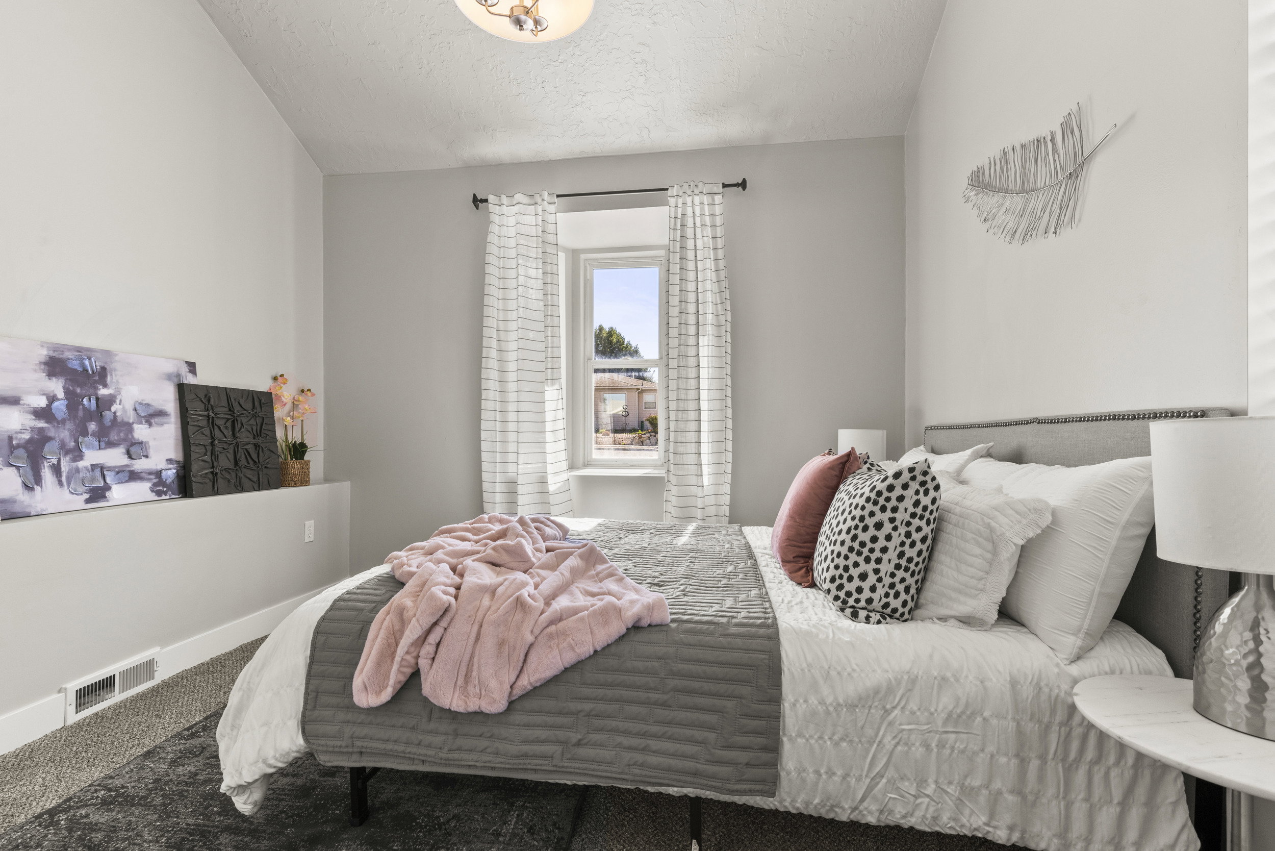Bedroom featuring a single window with vertical blinds, textured gray carpeting, and a built-in wall shelf