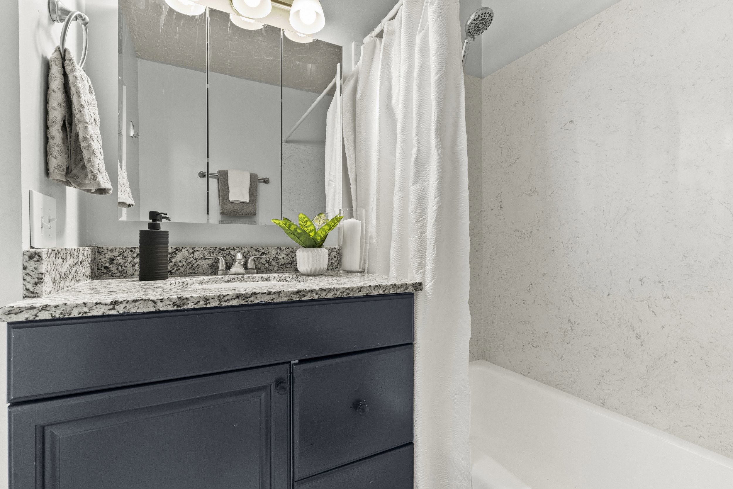 Bathroom featuring a dark blue vanity with a granite countertop, undermount sink, and polished chrome faucet