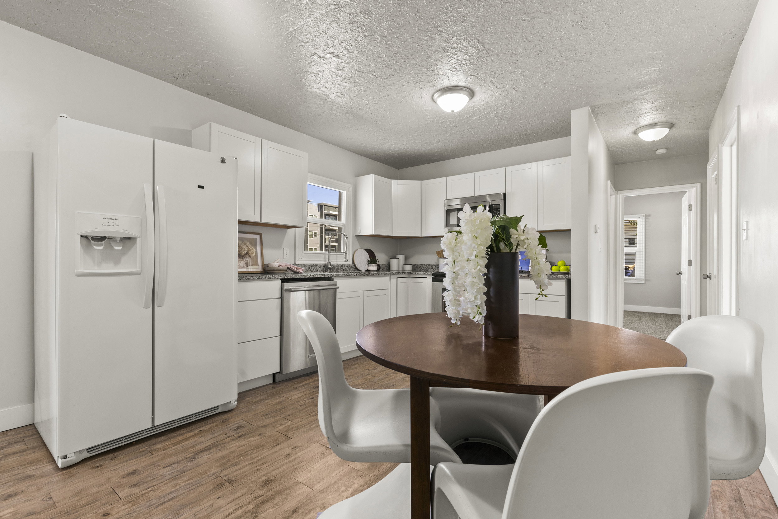 Open-concept kitchen featuring white cabinetry, light-toned countertops, and wood-finish flooring