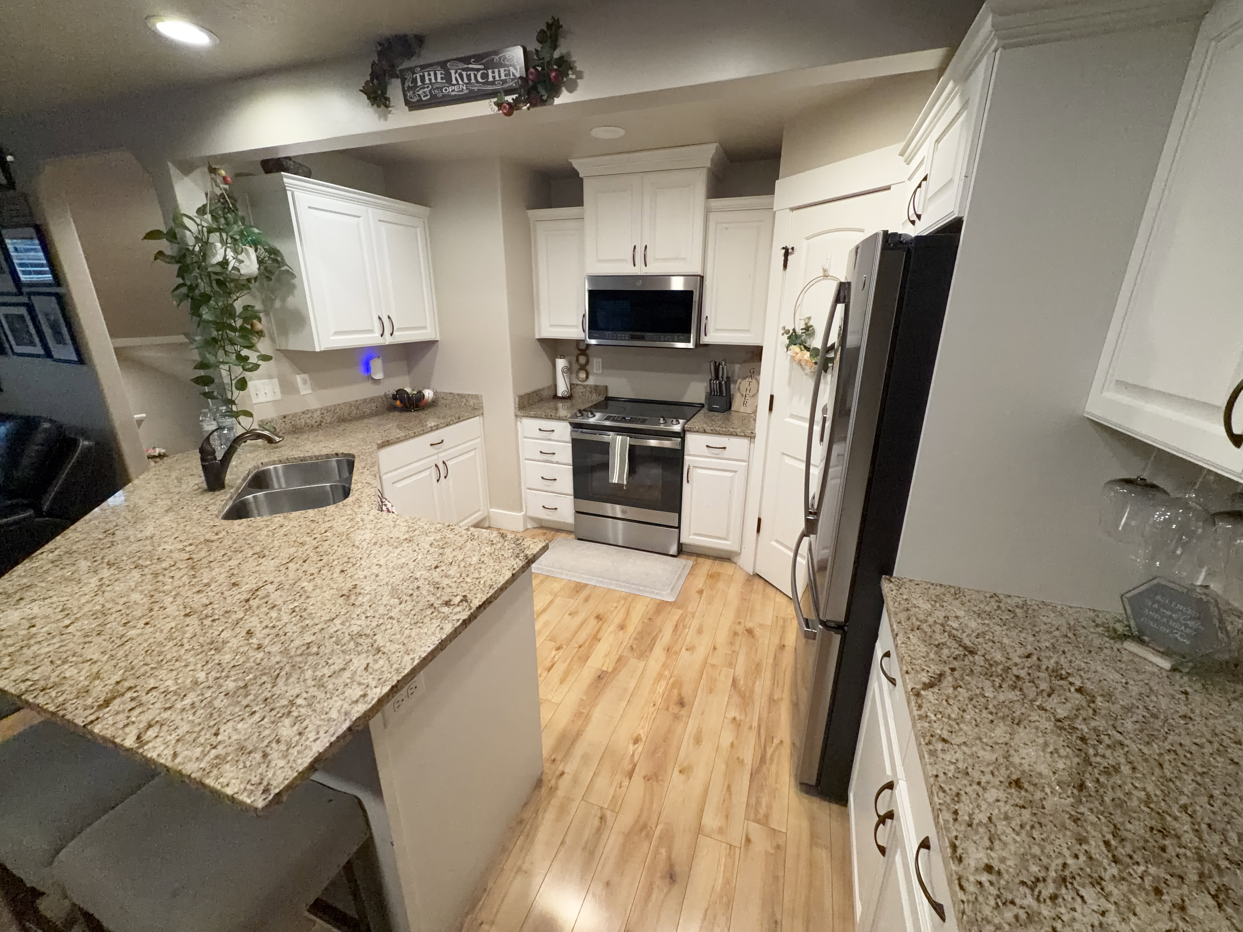 Kitchen featuring light wood-finish flooring, white cabinetry, and light-colored speckled countertops