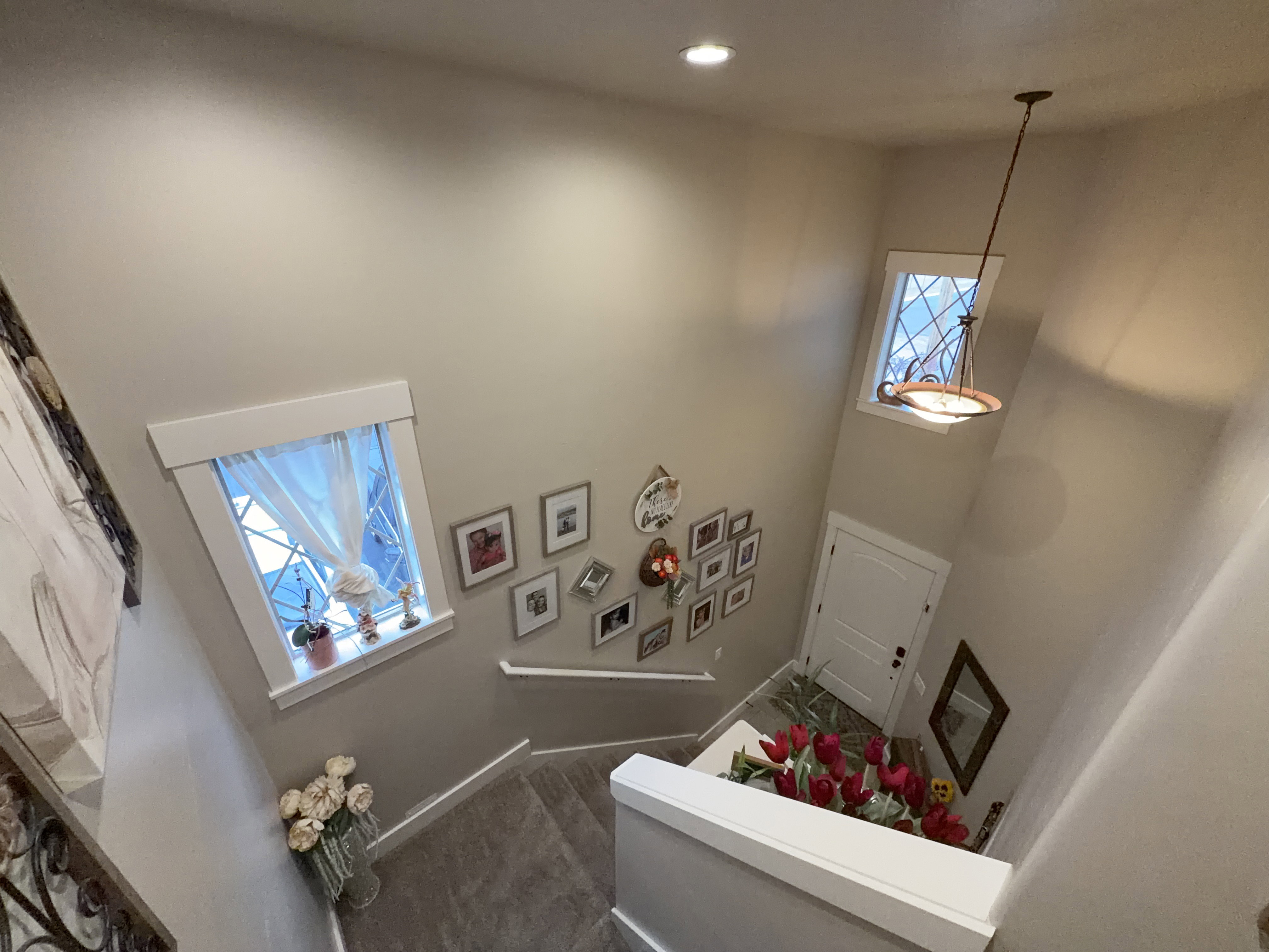 Stairwell featuring recessed lighting, a pendant fixture, two windows with decorative grilles, and a white paneled door