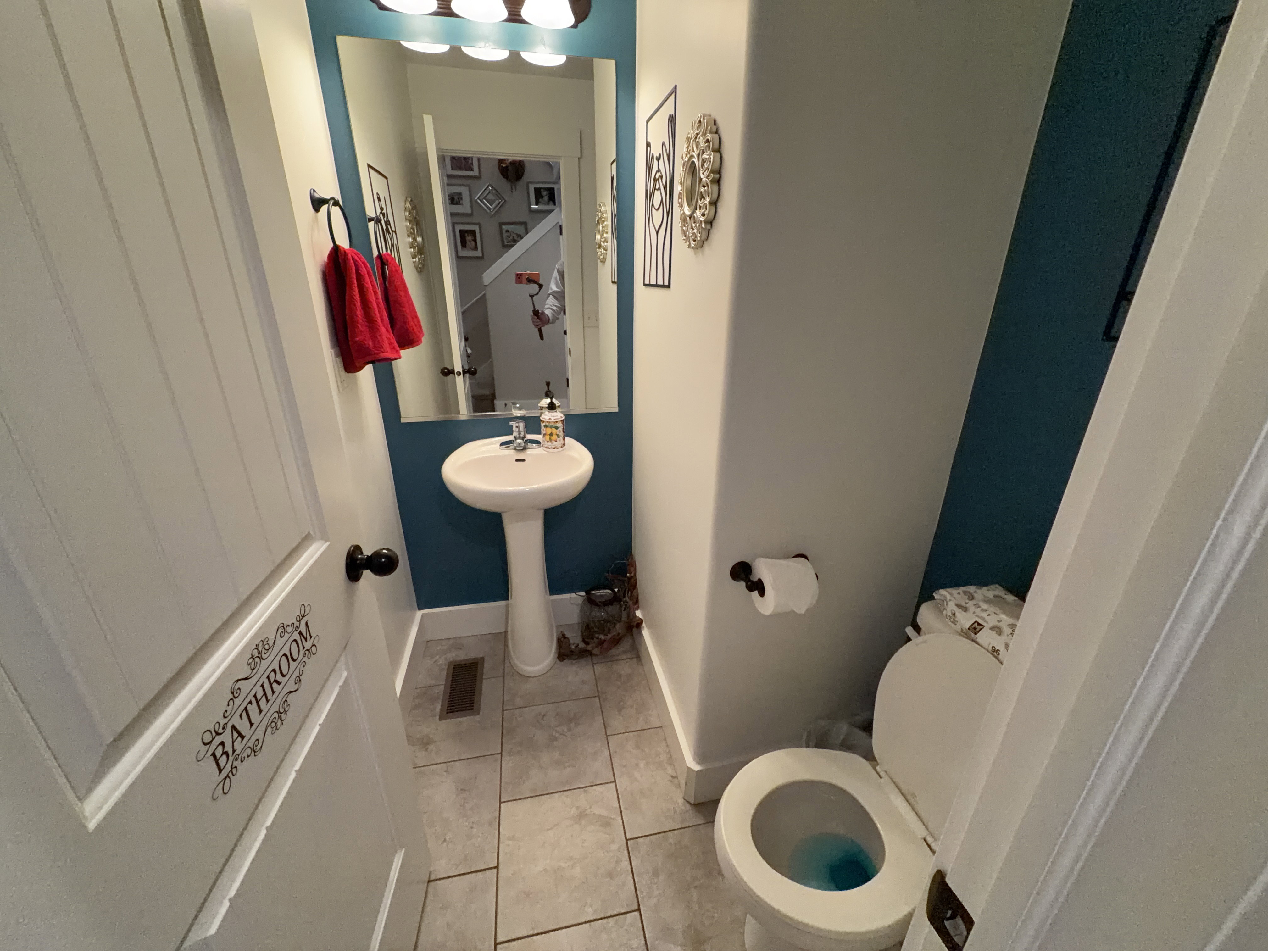 Pedestal sink with a wall-mounted mirror and overhead vanity lighting