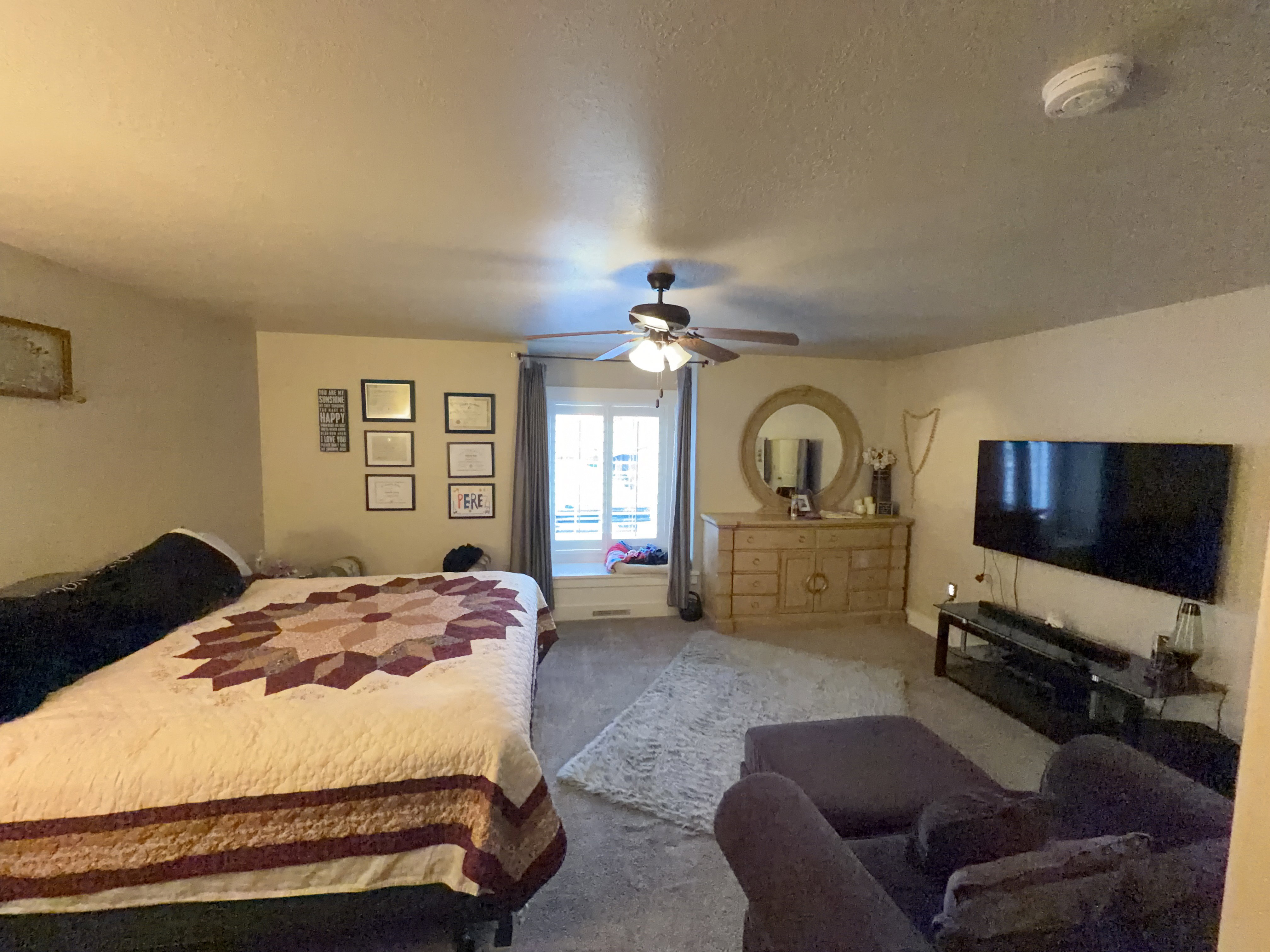 Spacious room featuring neutral-toned walls, a ceiling fan, and carpet flooring