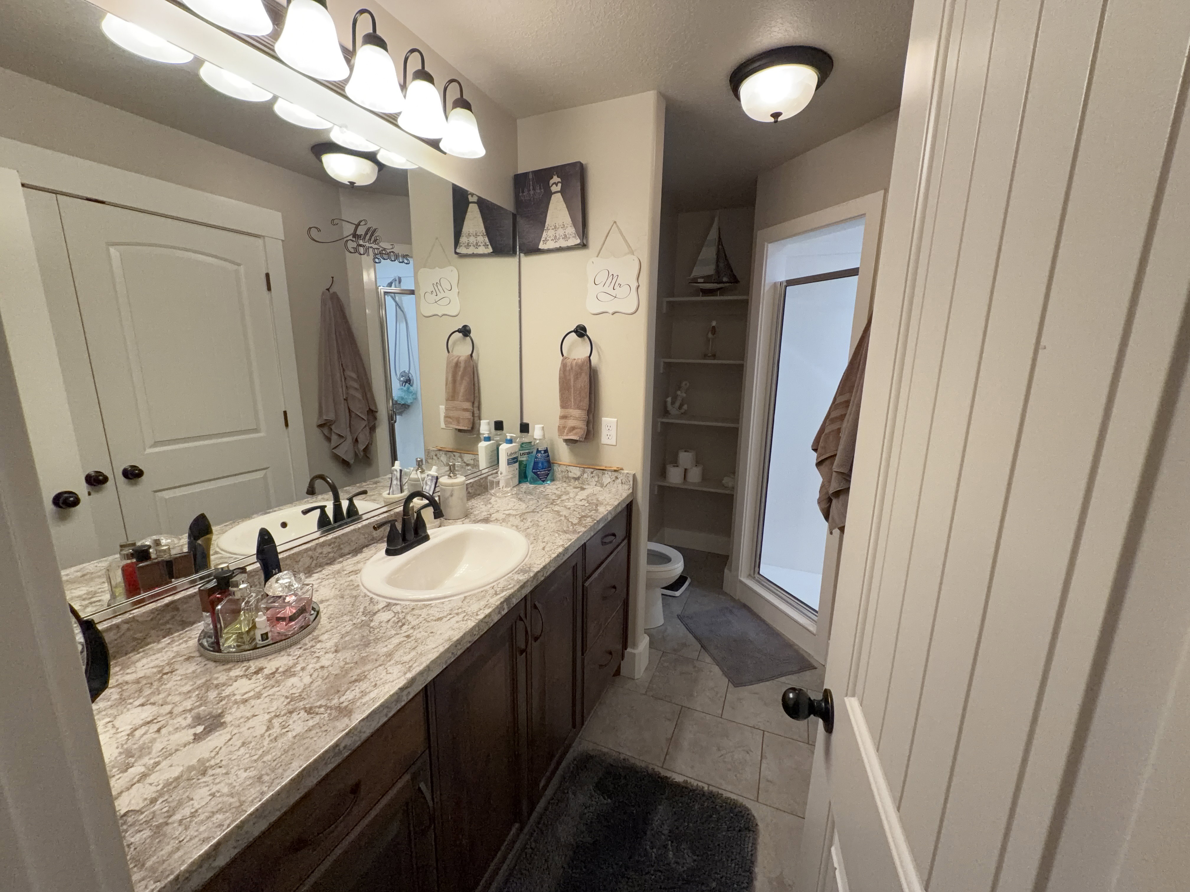 Dual sink vanity with dark wood-finish cabinetry and a neutral-toned countertop