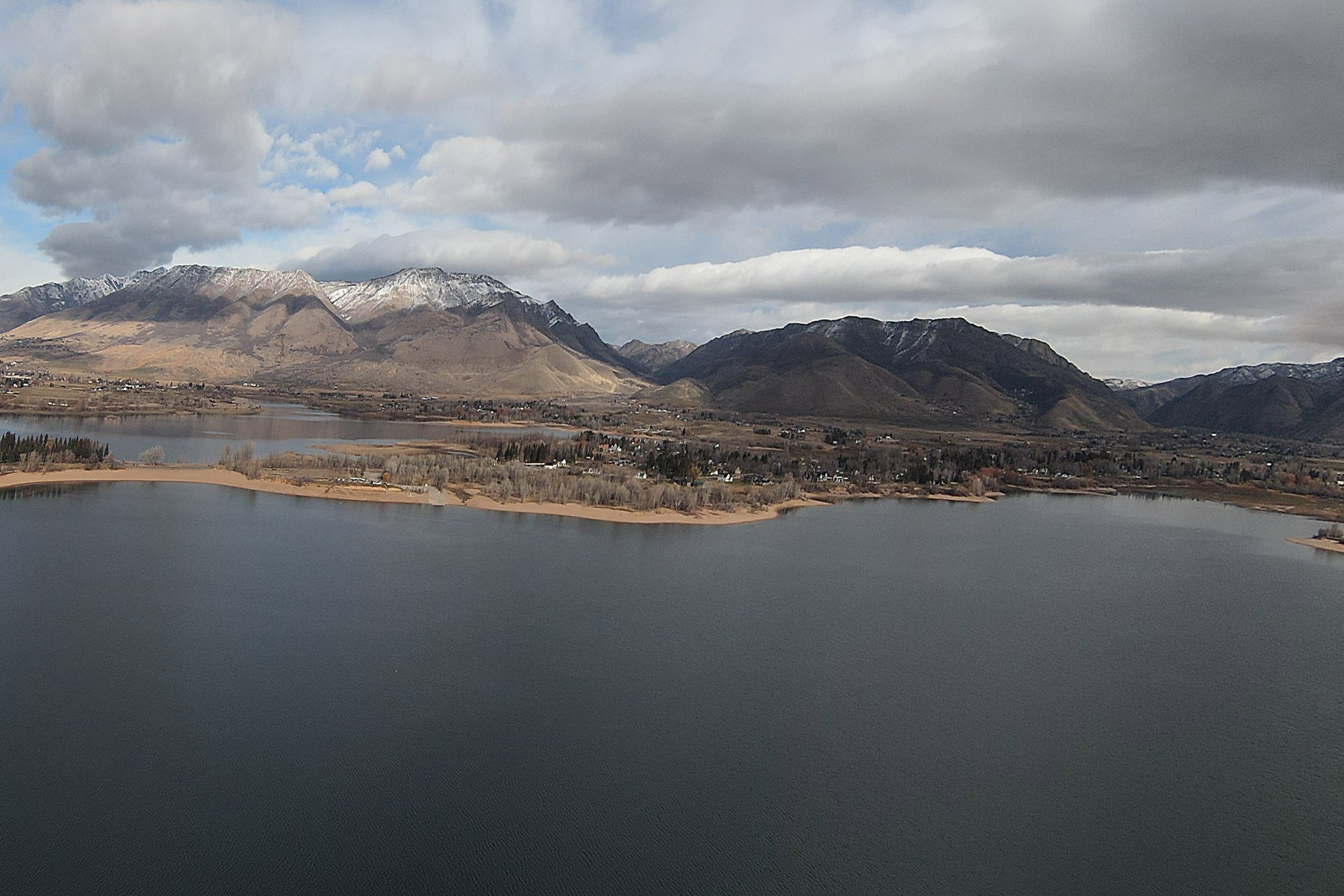 Expansive lake with surrounding land and distant mountains featuring snow-capped peaks