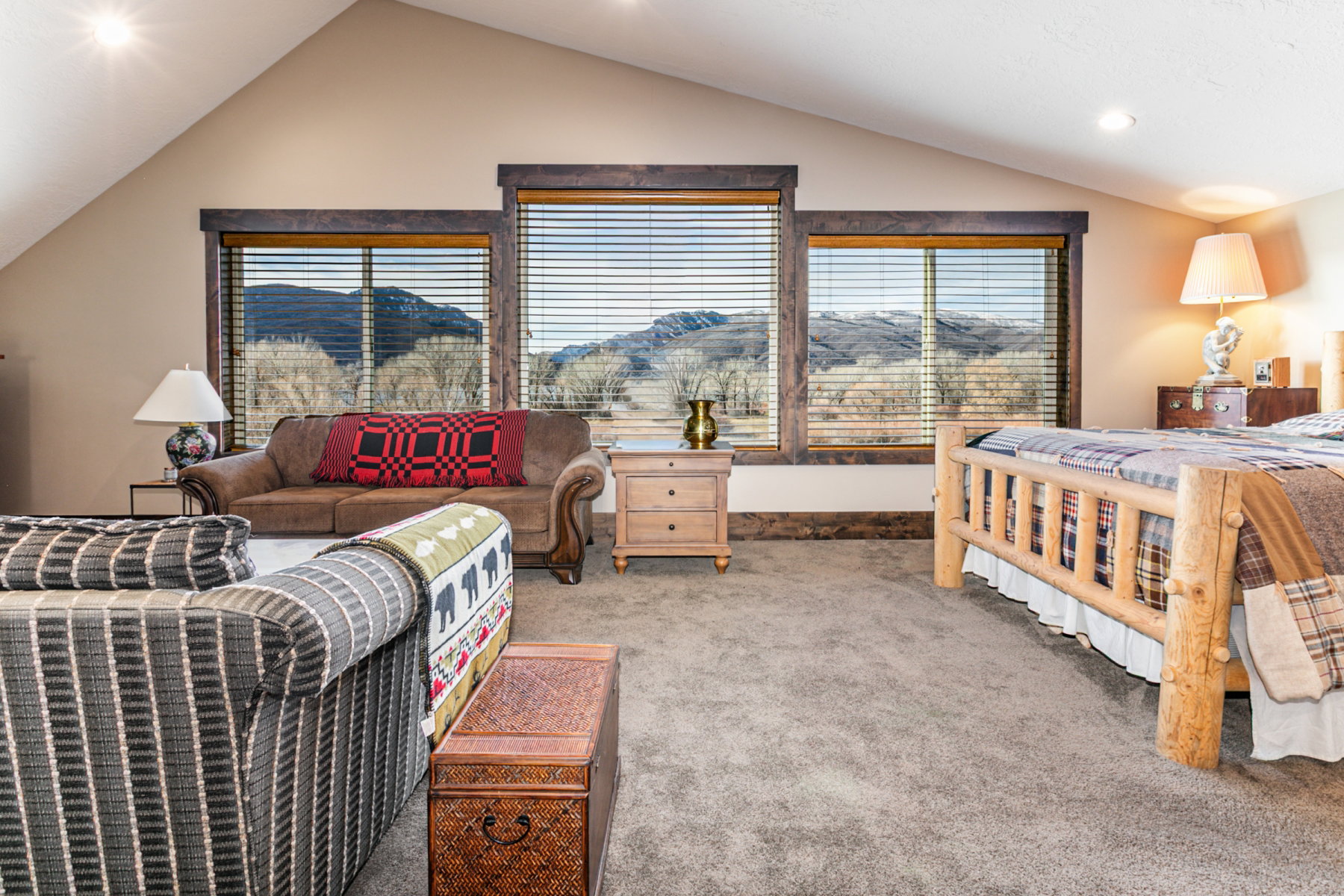Vaulted ceiling room featuring three large windows showcasing mountain scenery