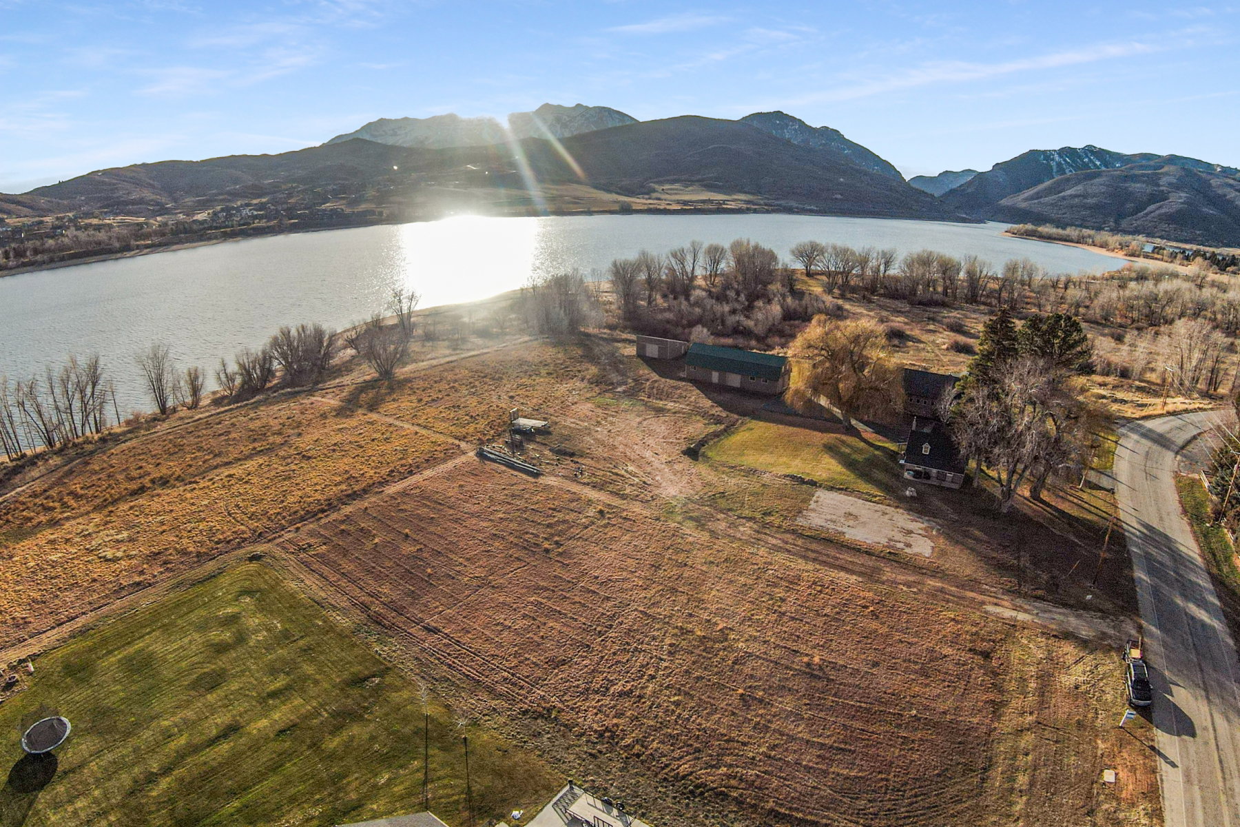 Expansive property parcel featuring a large lakefront, mountain backdrop, and direct paved road access