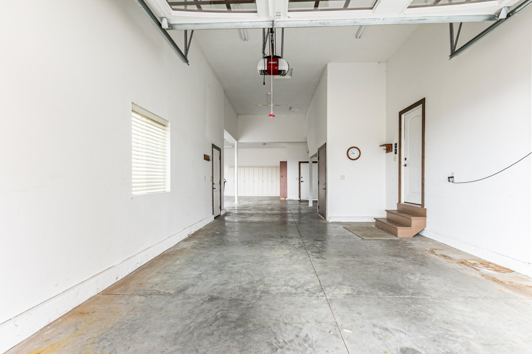 Expansive garage with high ceilings, multiple entry points, and a window with blinds providing natural light