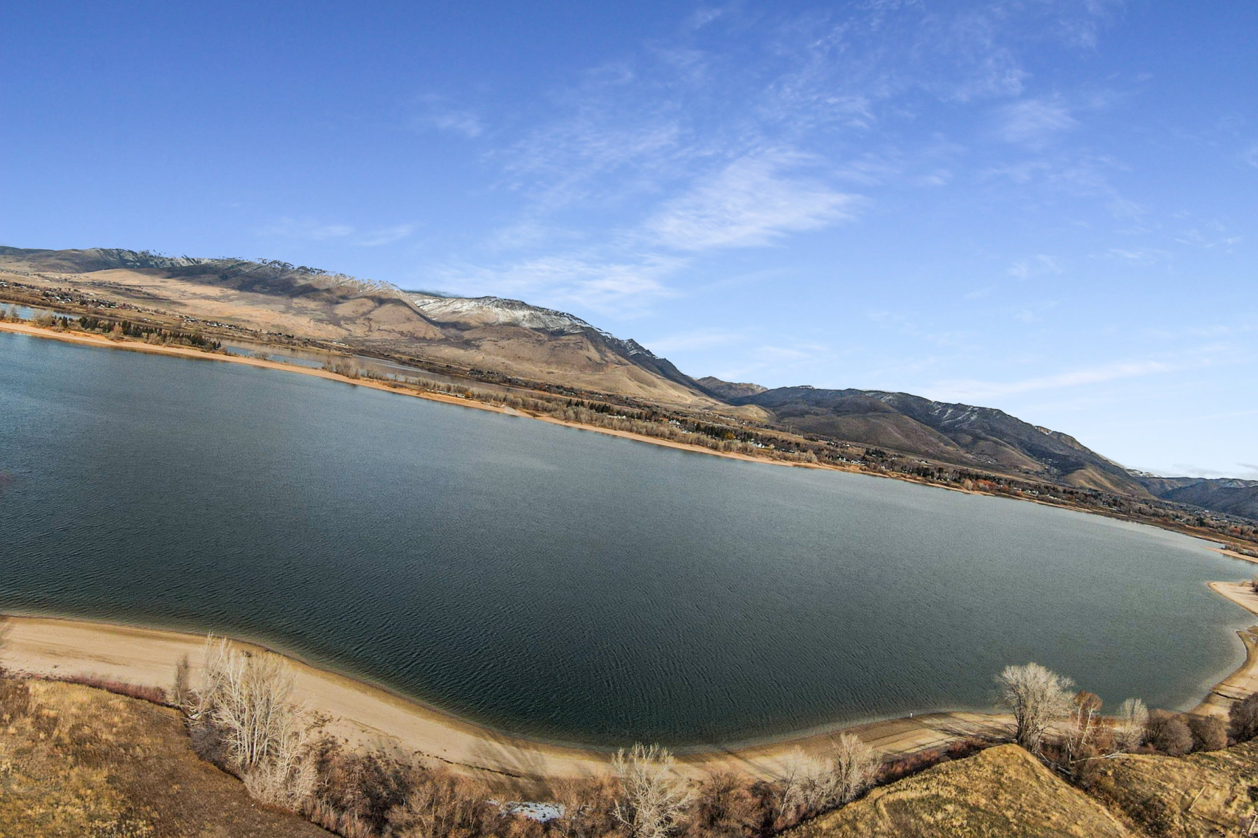 Expansive body of water bordered by a natural shoreline and distant mountains
