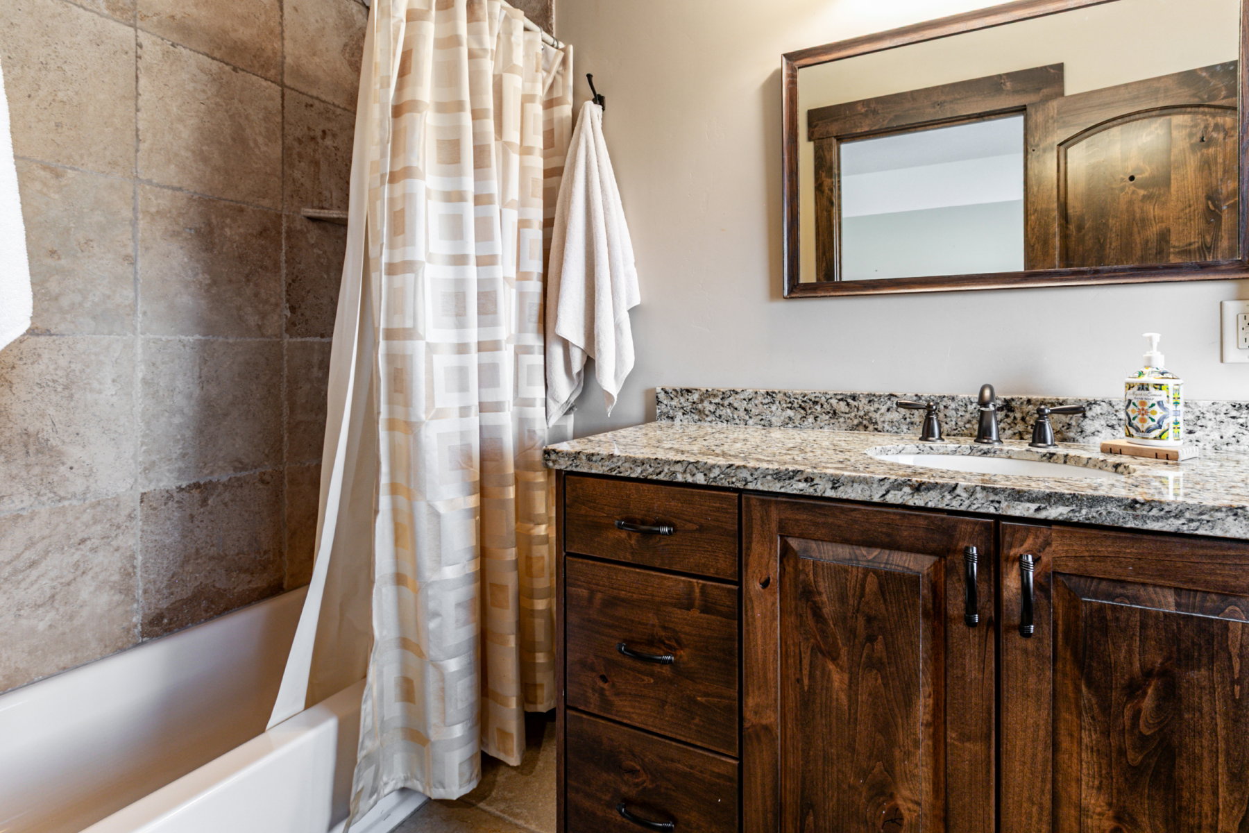 Bathroom vanity with a granite-style countertop, undermount sink, and dark wood cabinetry